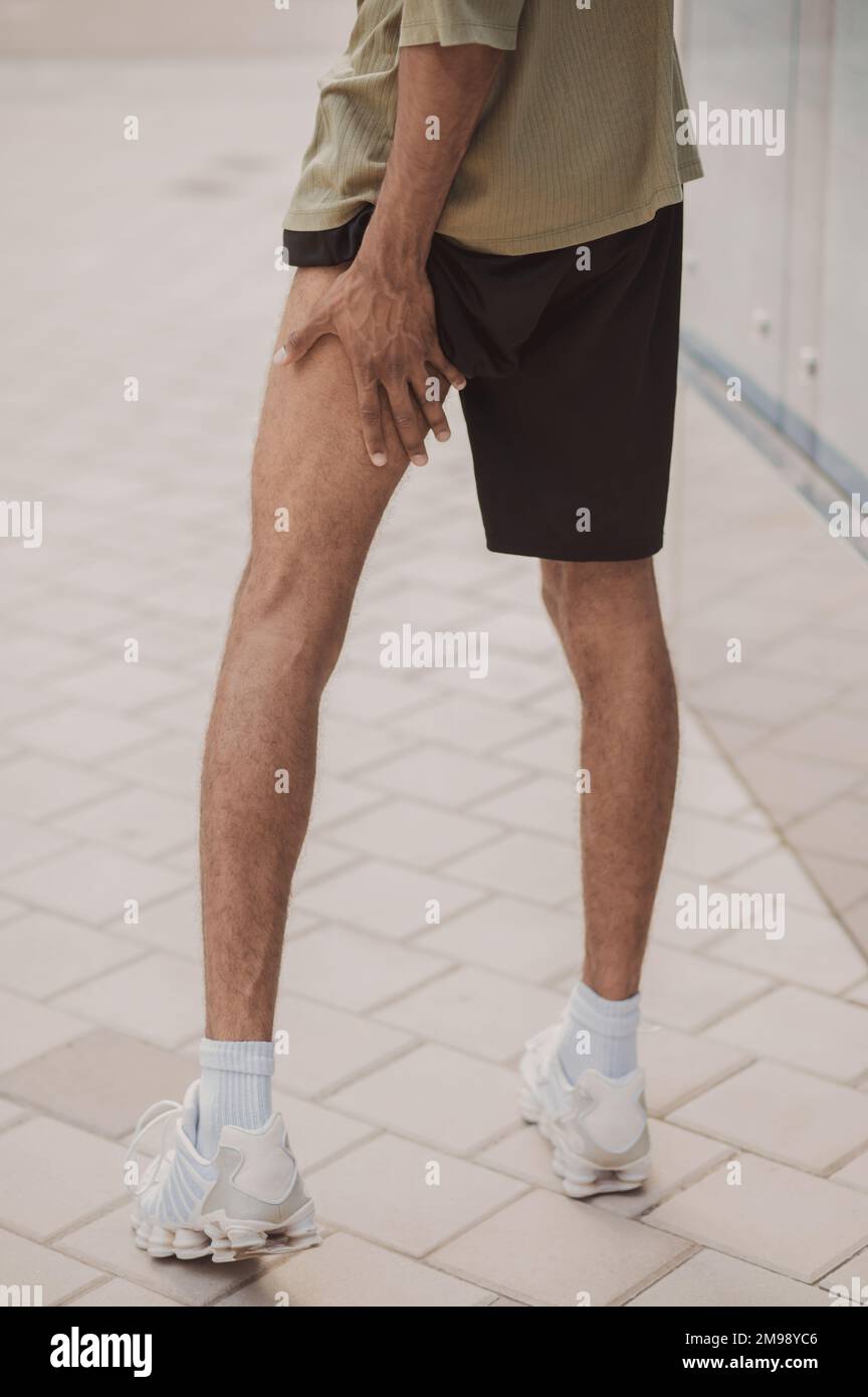 African American sportsperson suffering from thigh strain Stock Photo