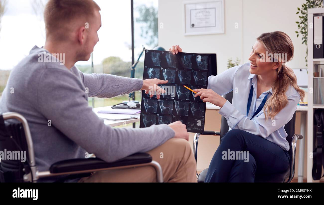 Woman Doctor Or GP In Office With Male Patient Looking At CT Or MRI Scan Stock Photo