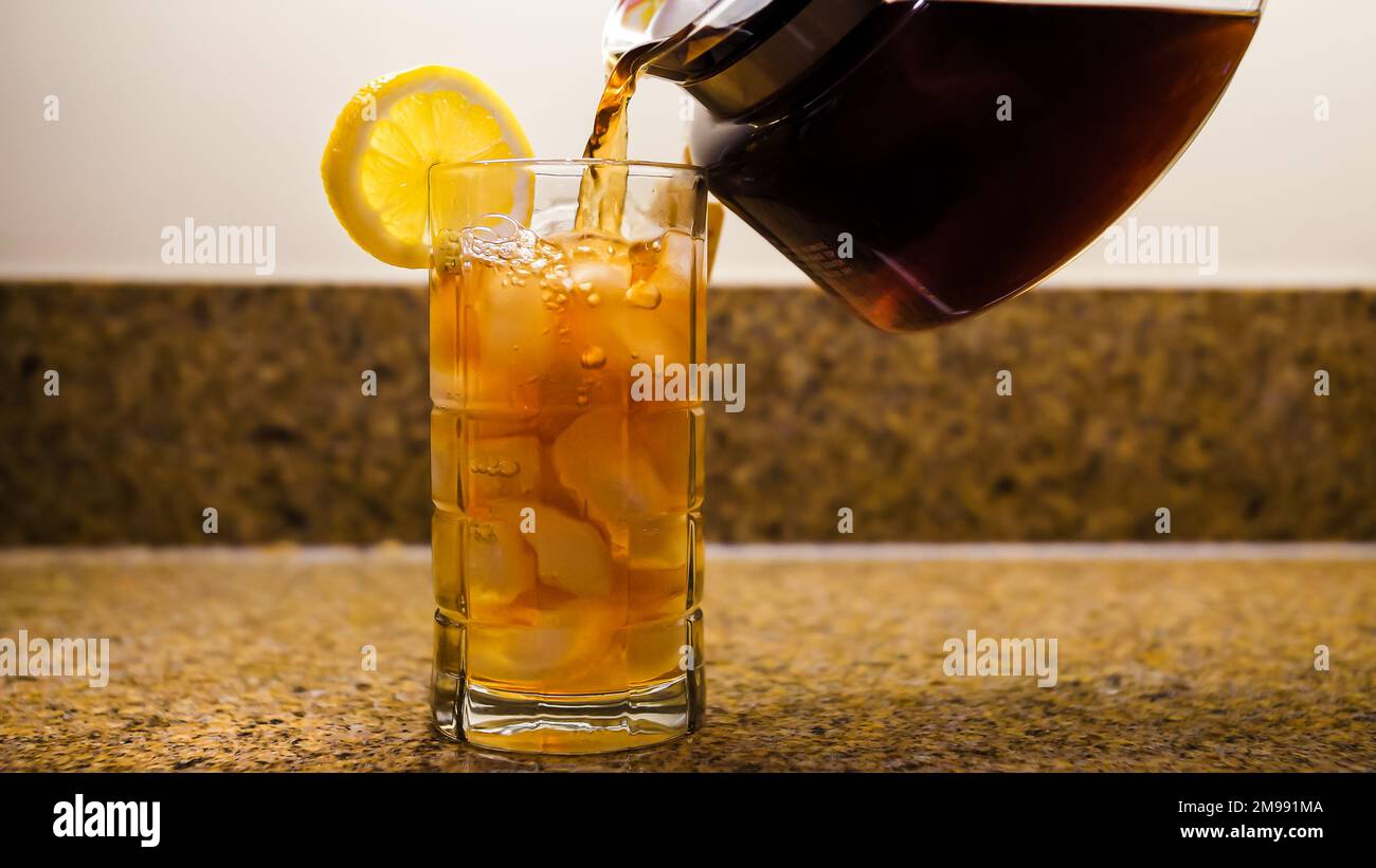 https://c8.alamy.com/comp/2M991MA/pouring-fresh-brewed-iced-tea-into-clear-glass-pitcher-of-tea-pouring-into-a-glass-of-ice-with-a-slice-of-lemon-2M991MA.jpg