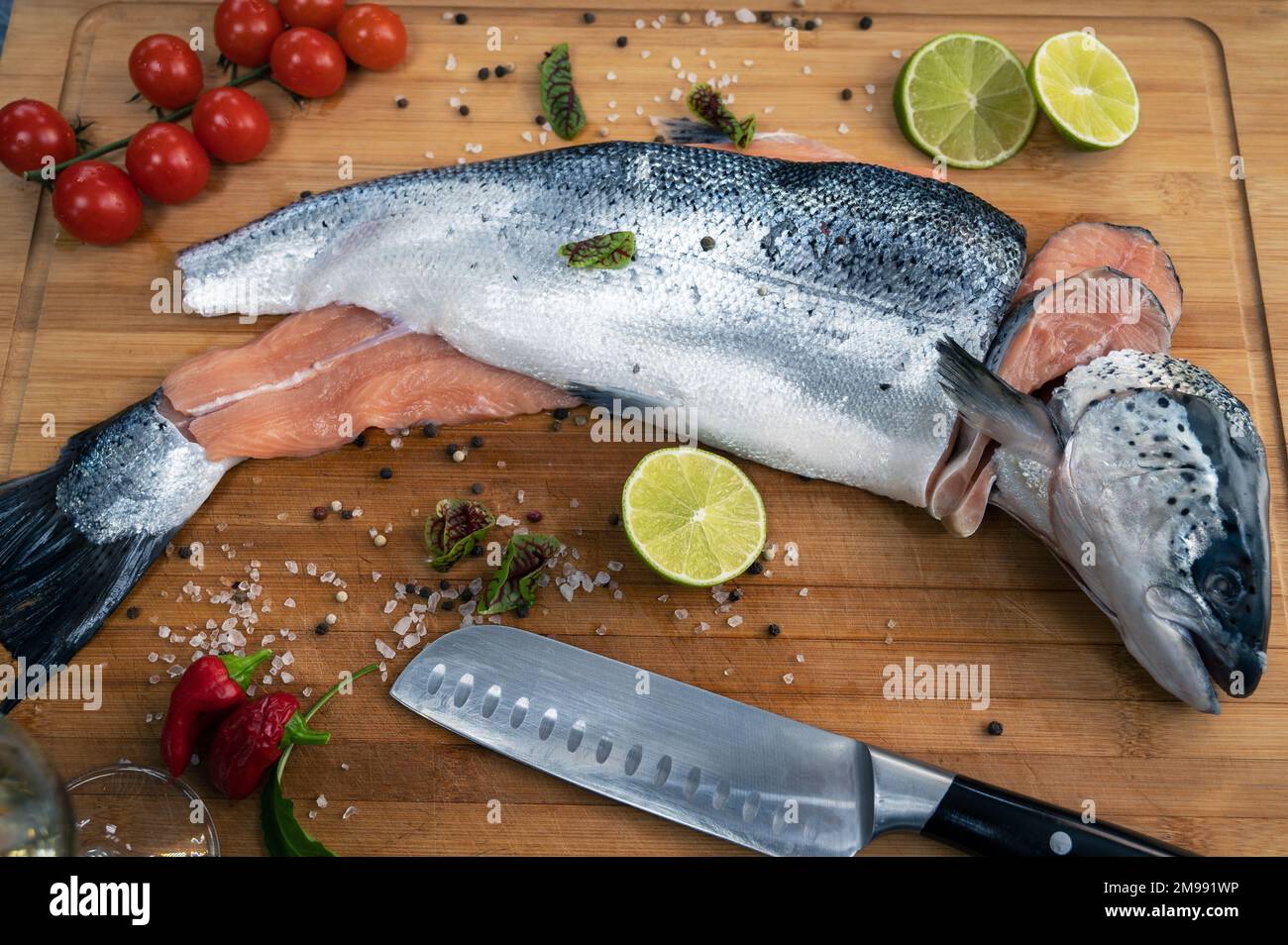 Fresh raw salmon fish on the kitchen wooden board with spices and lime Stock Photo