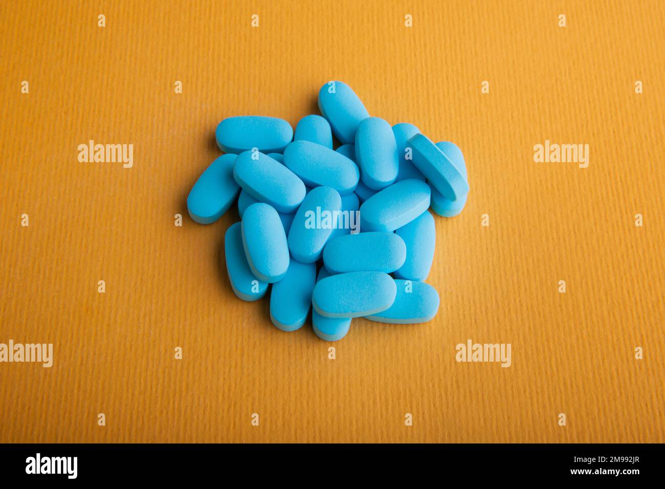 A high-angle shot of blue oval medicines on the yellow background. Stock Photo