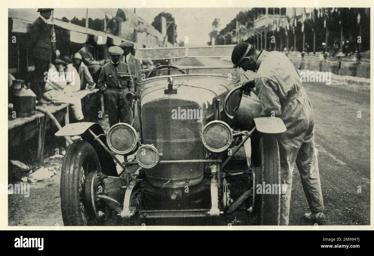 Early Motor Car Racing - Sunbeam car at Le Mans Race, 1925. Filling the separate oil tank. Mud and dust are thickly plastered on the lamps. Stock Photo