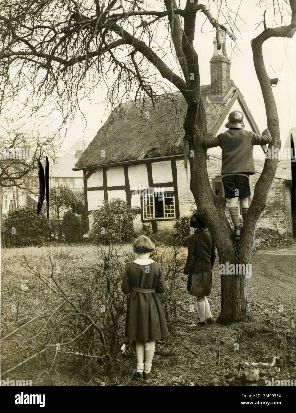 A haunted 300-year-old Tithe Barn near Altrincham, Cheshire, to be rebuilt, complete with Black Boggart, by the Ancient Monuments Society, March 1936. Seen here with three children in the garden. Stock Photo