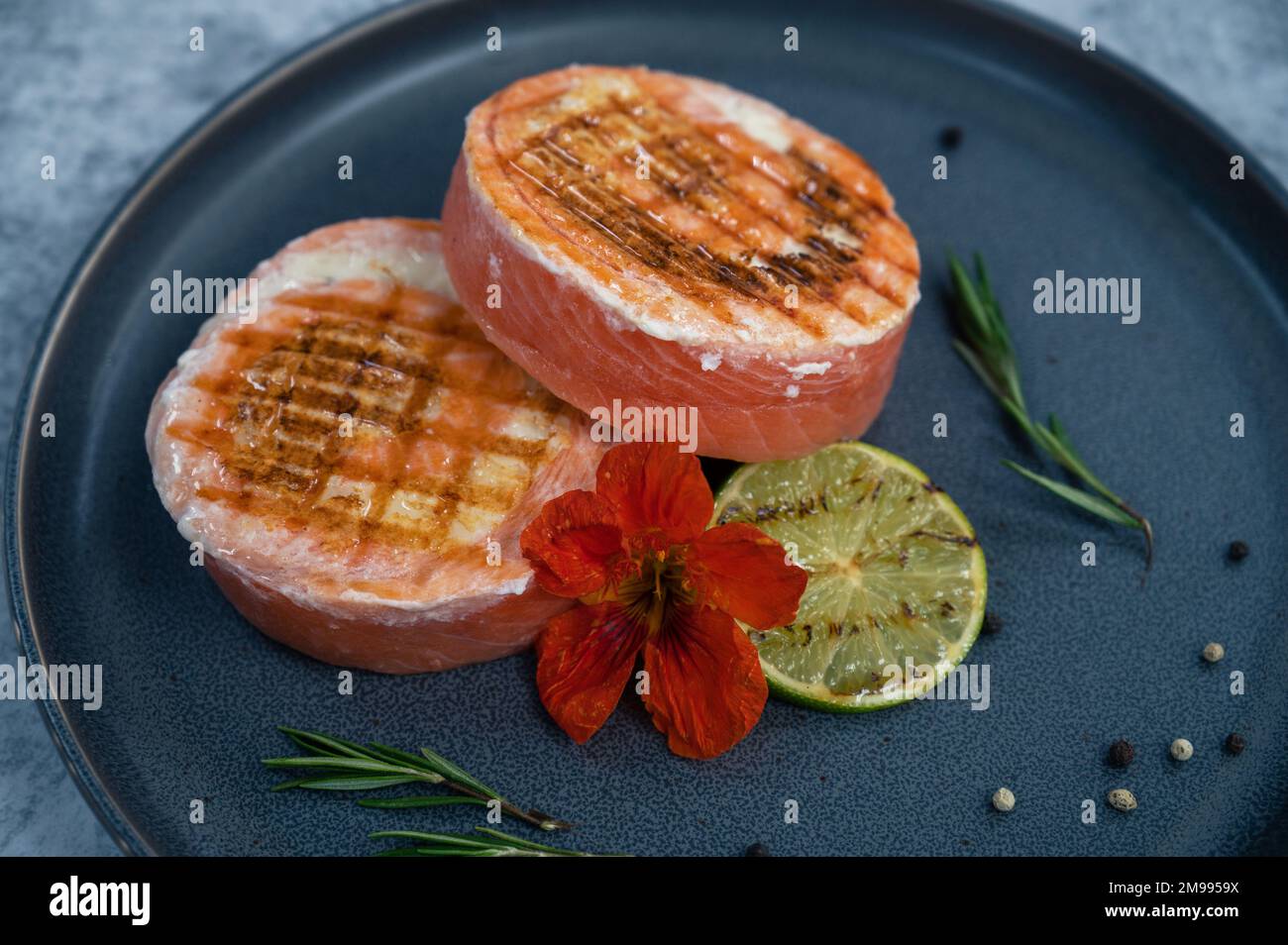 Grilled salmon roll with mozzarella. Decorated with greens lime and edible flower Stock Photo