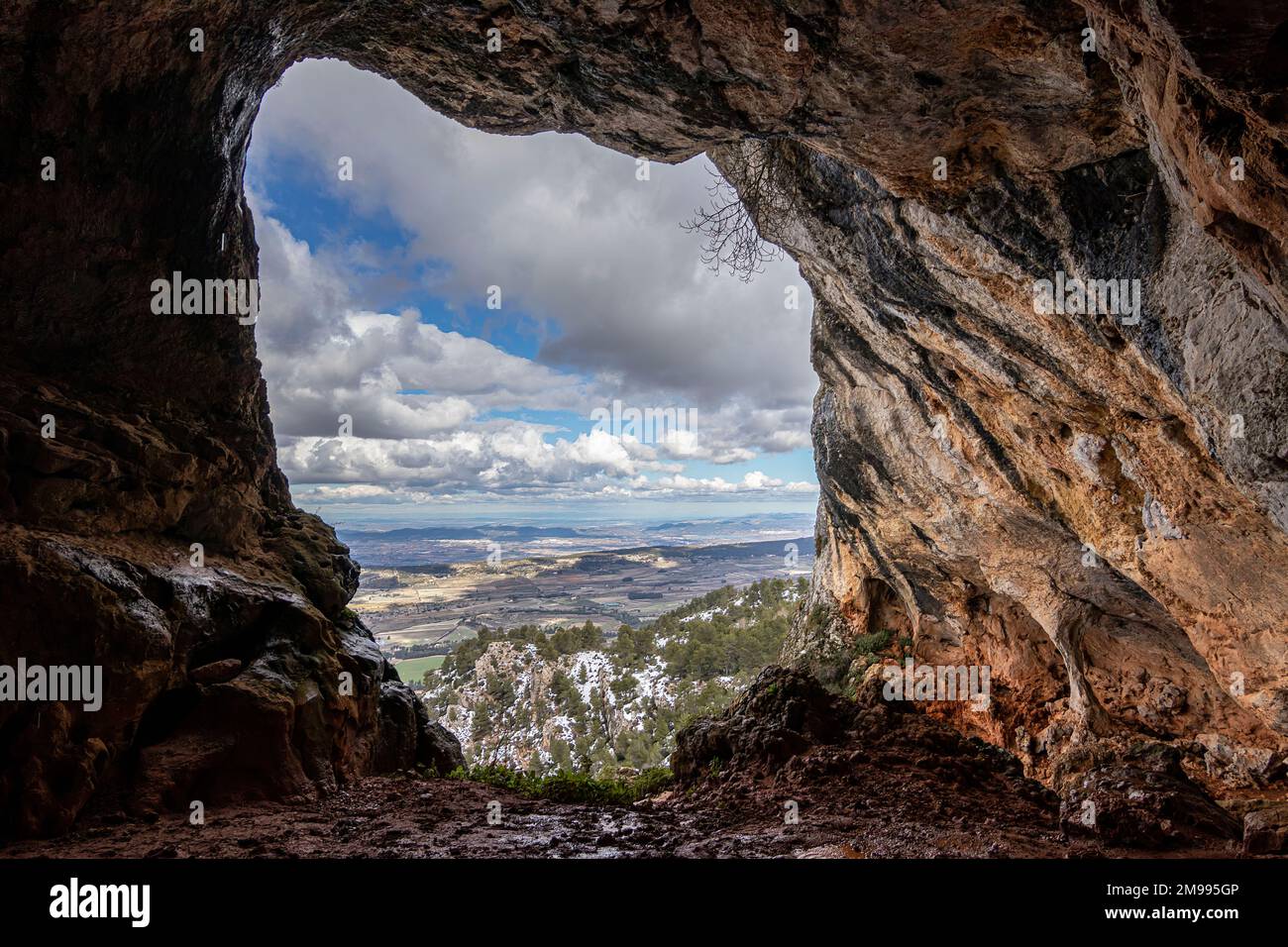 Bolumini cave from the inside, in the background a snowy landscape with blue sky. Mariola natural park ,Agres, Alicante, Spain. Stock Photo