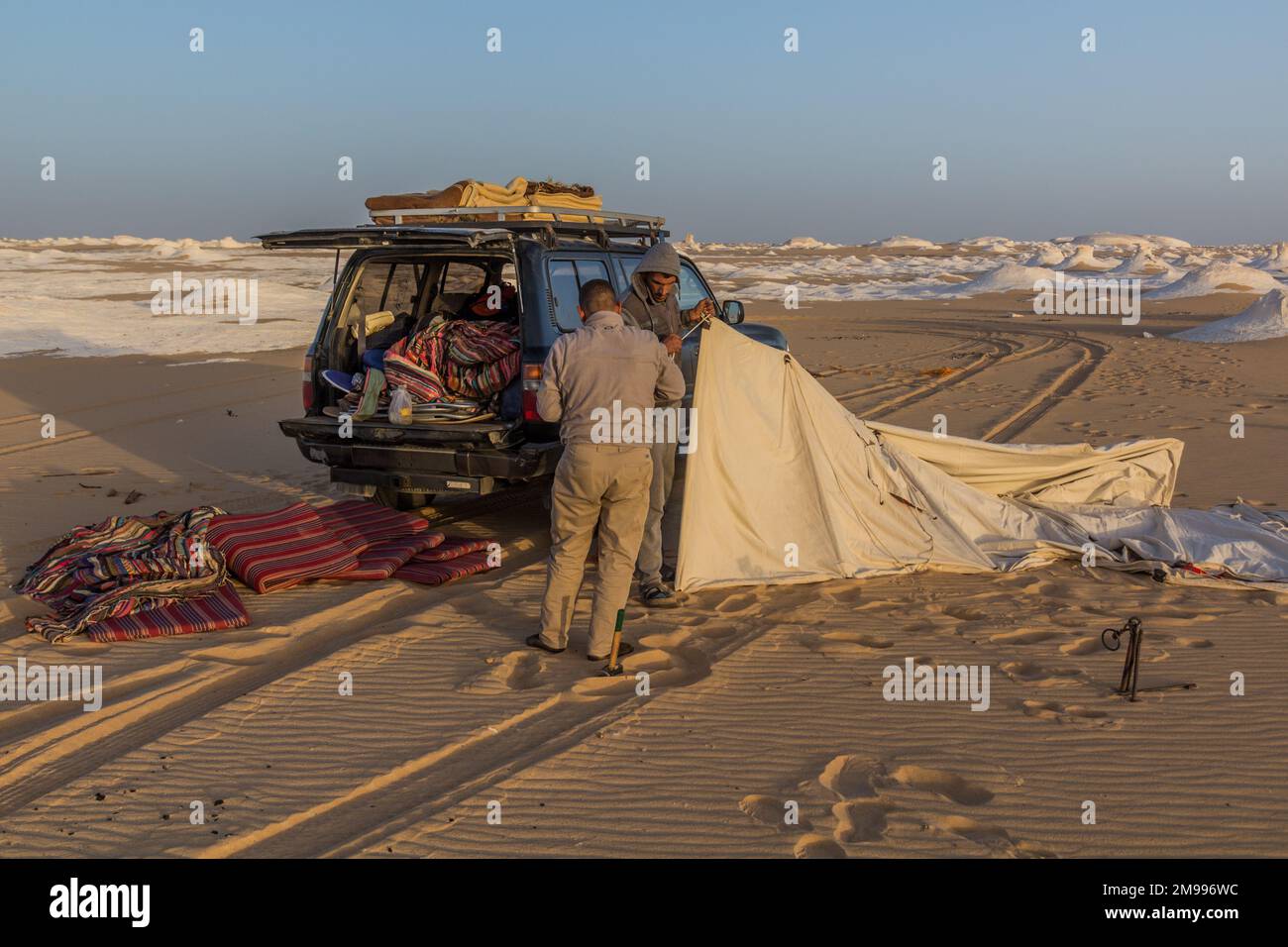 WHITE DESERT, EGYPT - FEBRUARY 6, 2019: Tour guides setting up a tent in the White Desert, Egypt Stock Photo