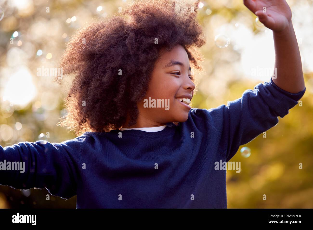 Smiling Boy Outdoors Having Fun Playing With Bubbles In Garden Stock Photo