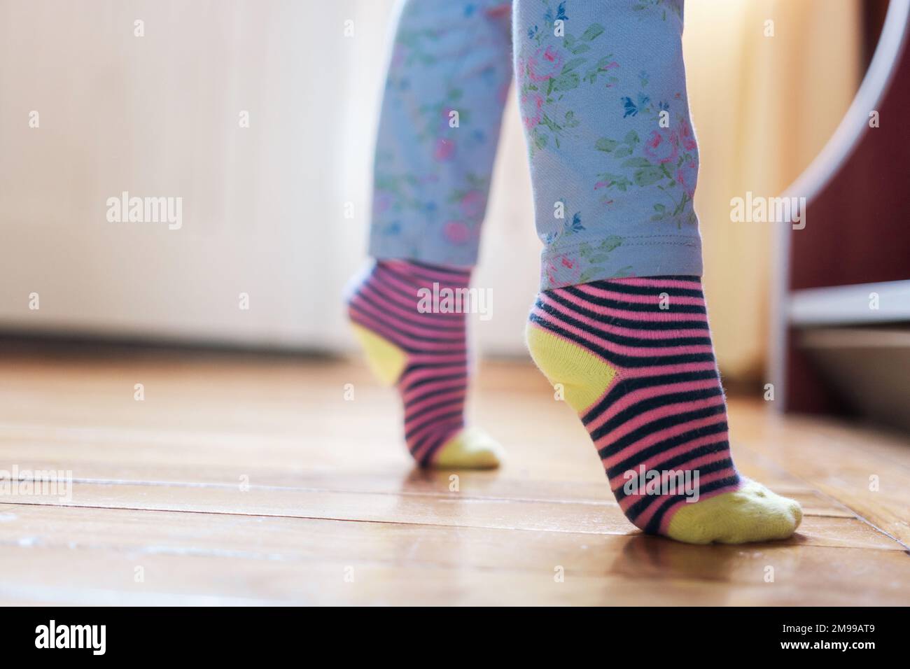 Little girl's legs standing tiptoe at home Stock Photo