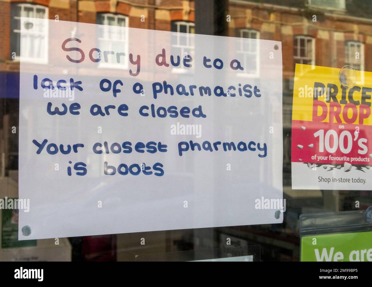 Sign in pharmacy chemist window, shop closed due to lack of pharmacist. Chemist shop, pharmacy store closed. Lloyds, High St, Sidmouth Stock Photo