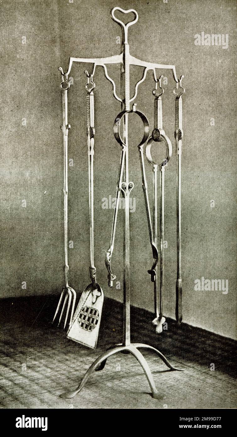 Stand of fire irons in polished wrought iron, designed by Ernest Gimson. Stock Photo