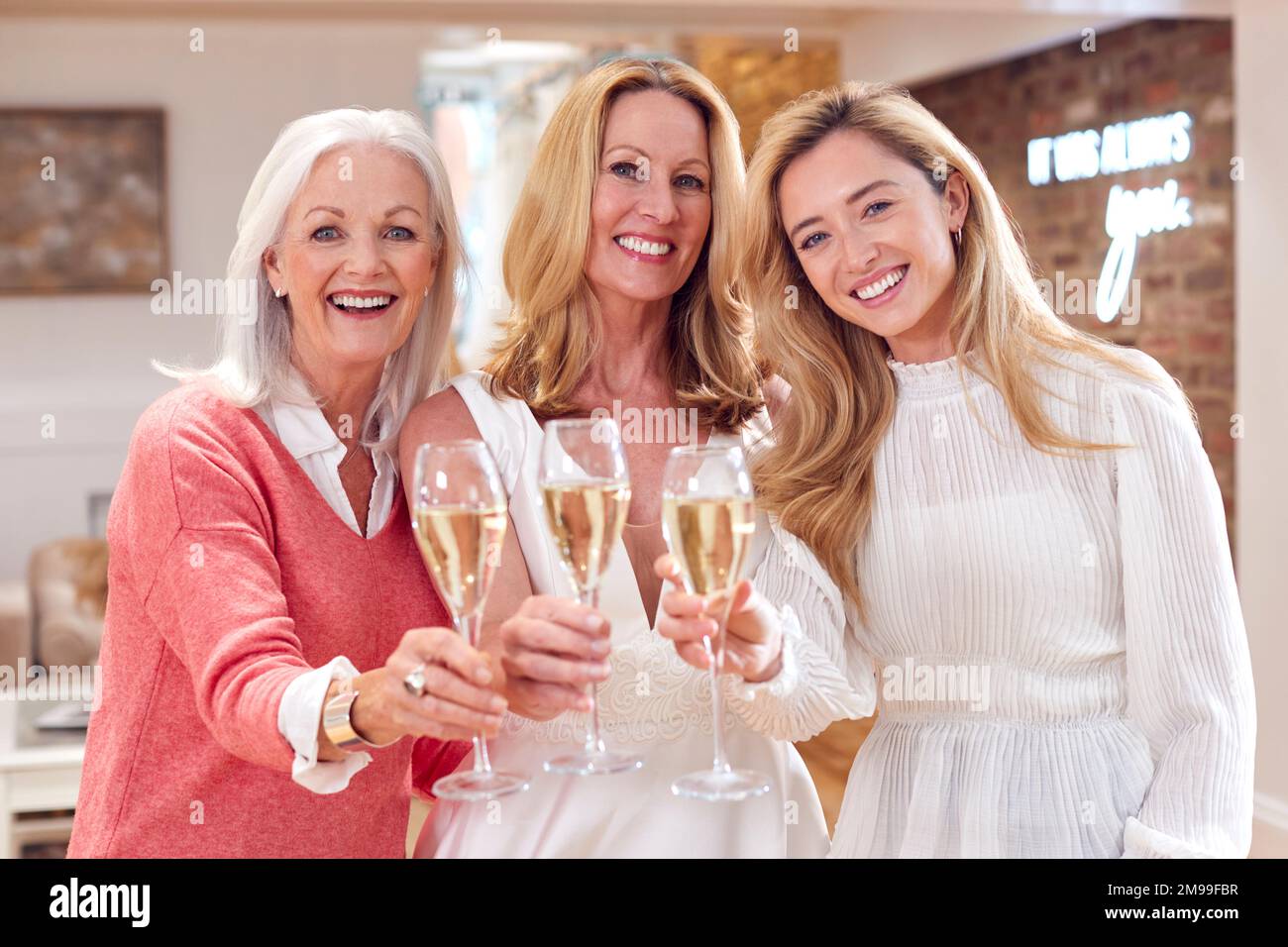 Portrait Of Grandmother With Adult Daughter And Granddaughter Trying On Wedding Dress In Store Stock Photo