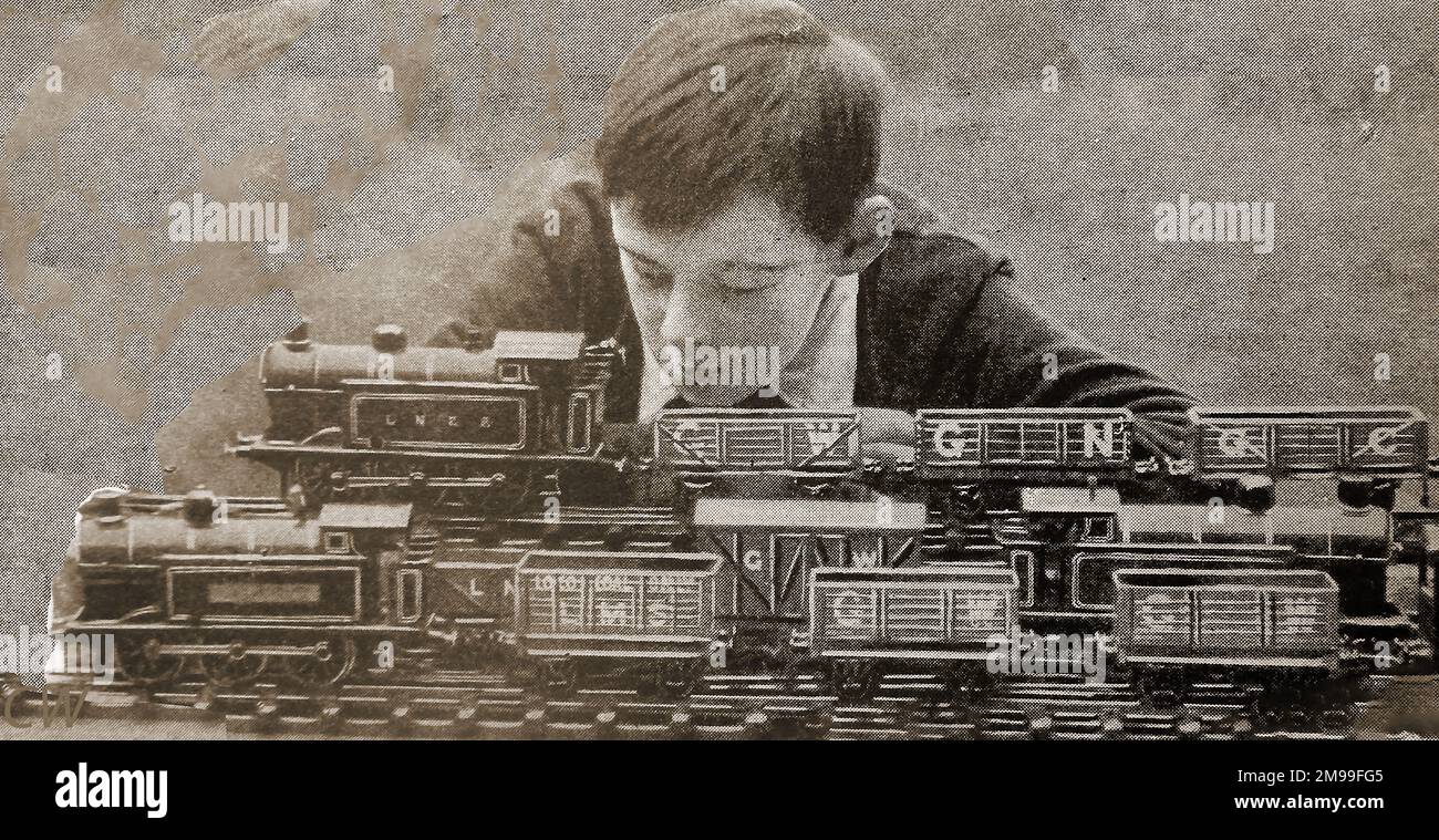 1930- A schoolboys plays with his model railway goods train sets Stock Photo