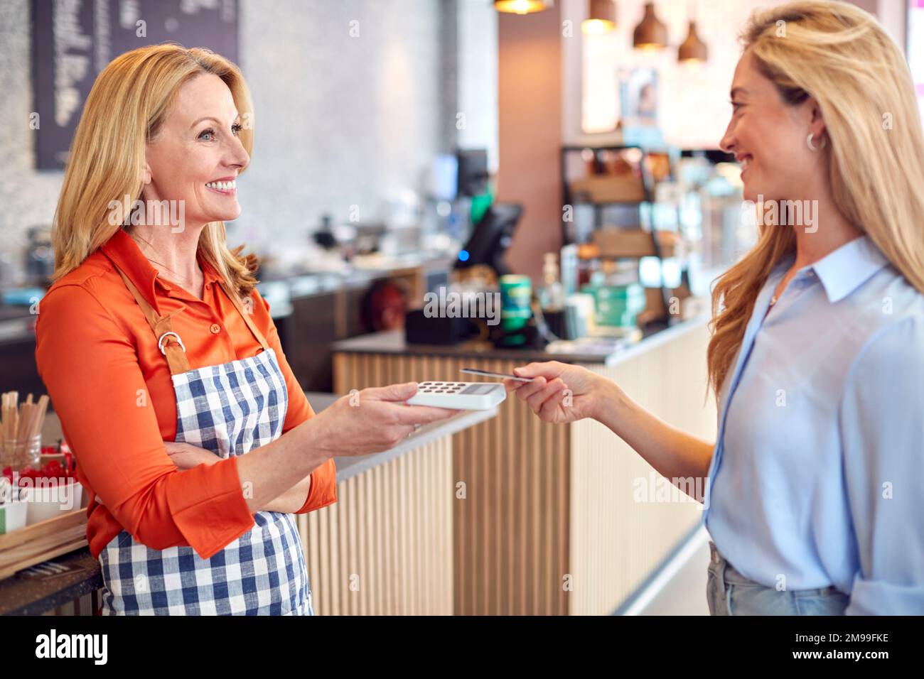 Female Customer In Coffee Shop Making Contactless Payment With Card Stock Photo