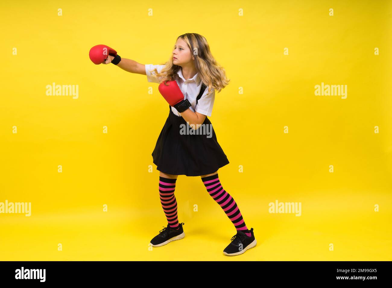 An adorable little girl boxer practicing punches in studio Stock Photo