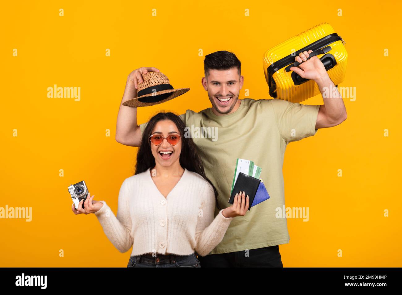Happy glad millennial arabic husband and wife with hat, suitcase, photo camera and tickets rejoice to travel Stock Photo