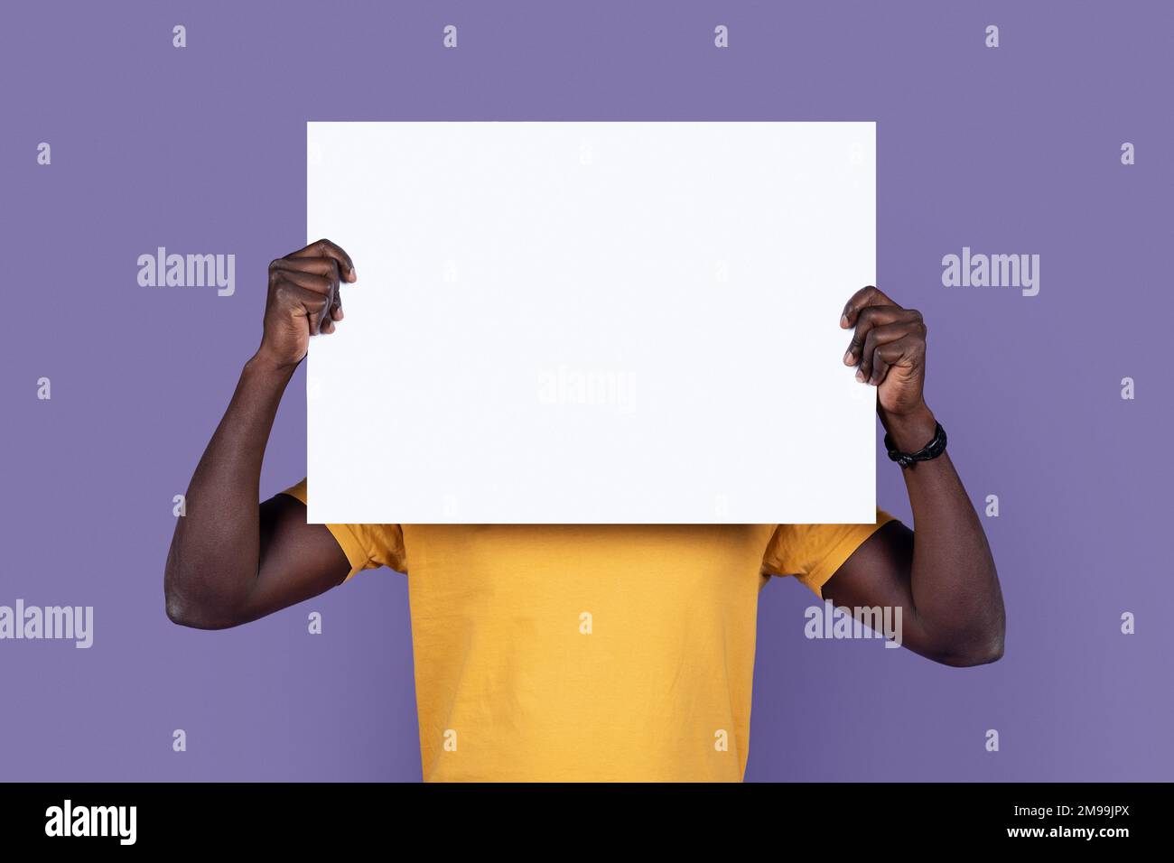 Black man hiding behind empty advert board Stock Photo