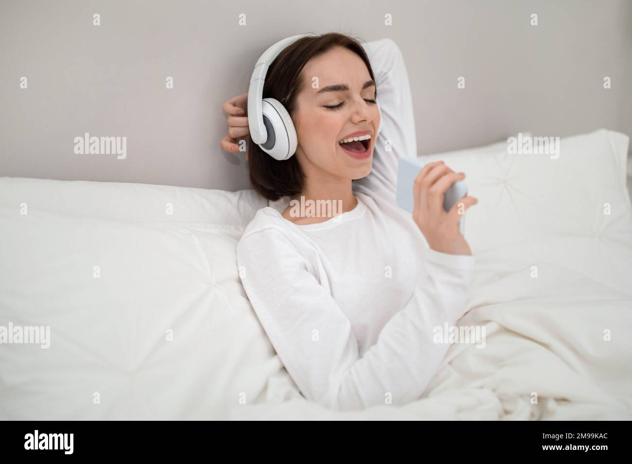 Joyful young woman having fun in bed at home Stock Photo - Alamy
