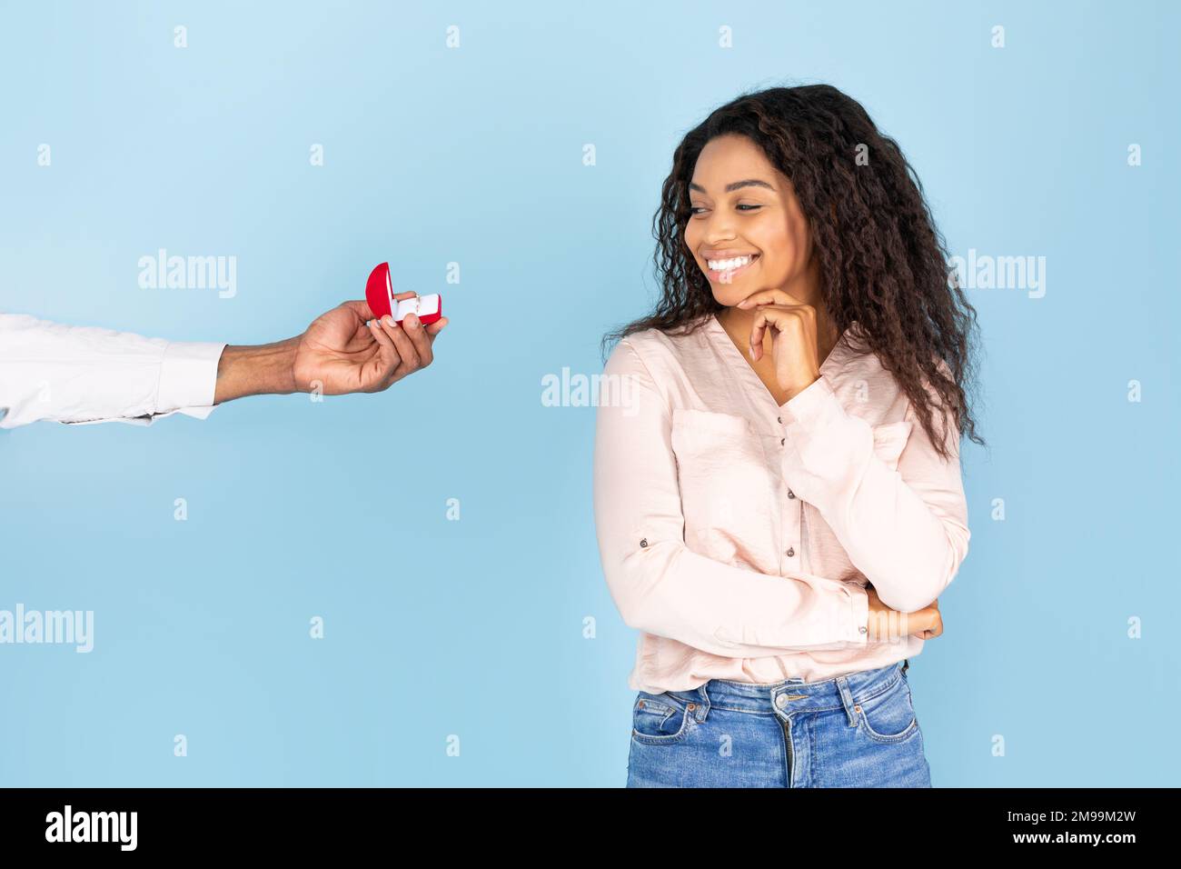 Marriage proposal. Man giving ring in box to happy black lady isolated on blue background, studio shot, copy space Stock Photo