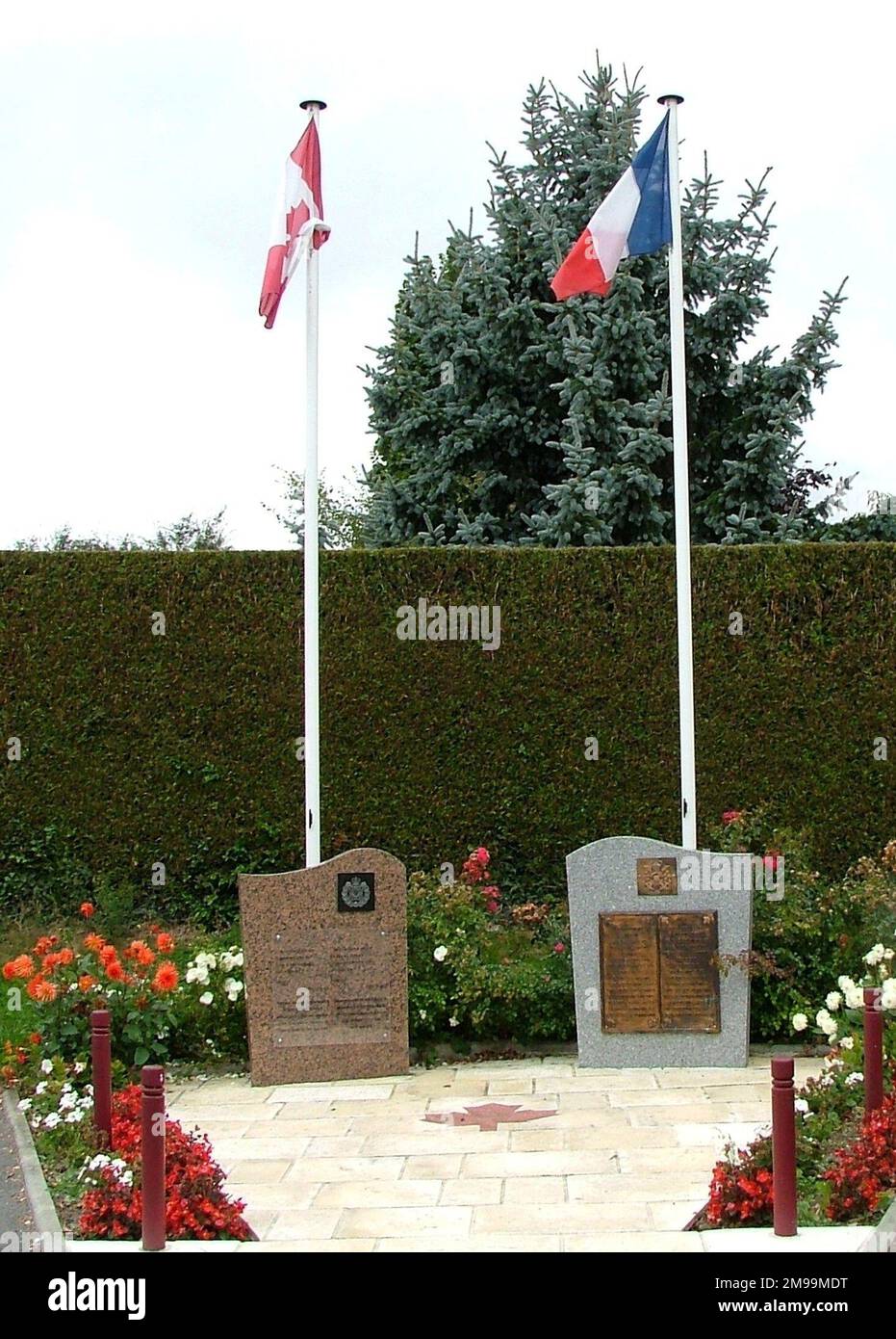 This double memorial has a plaque to the Rifles on the left and to the Scottish on the right. Between them is a poem by Paul Eluard. In front is a board describing the liberation of the village (Putot-en-Bessin) and the casualties, including 98 Germans & 256 Canadians, of whom 45 were massacred at Audrieu Chateau. Stock Photo