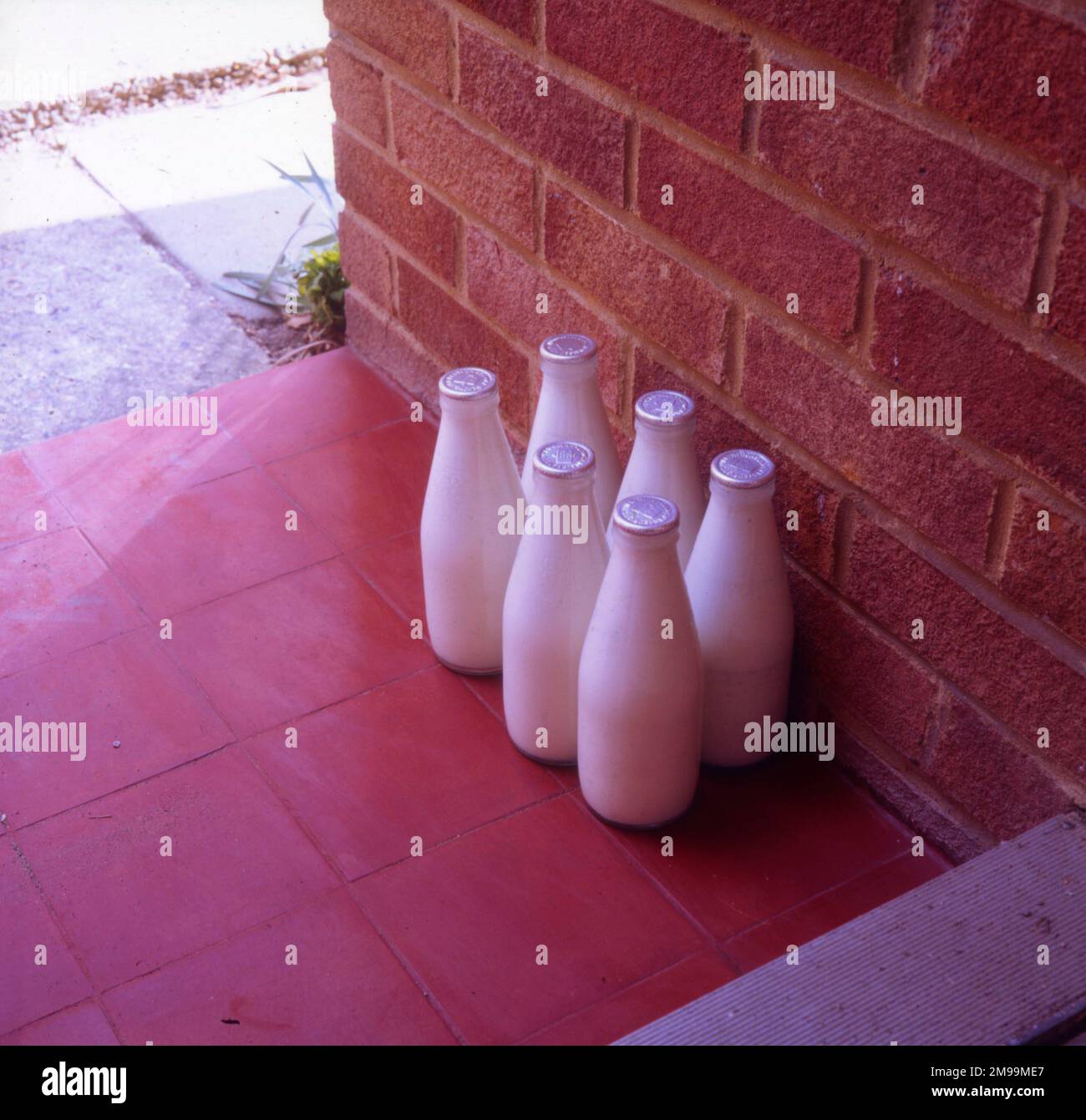 Six bottles of silver-top milk on the doorstep. Stock Photo