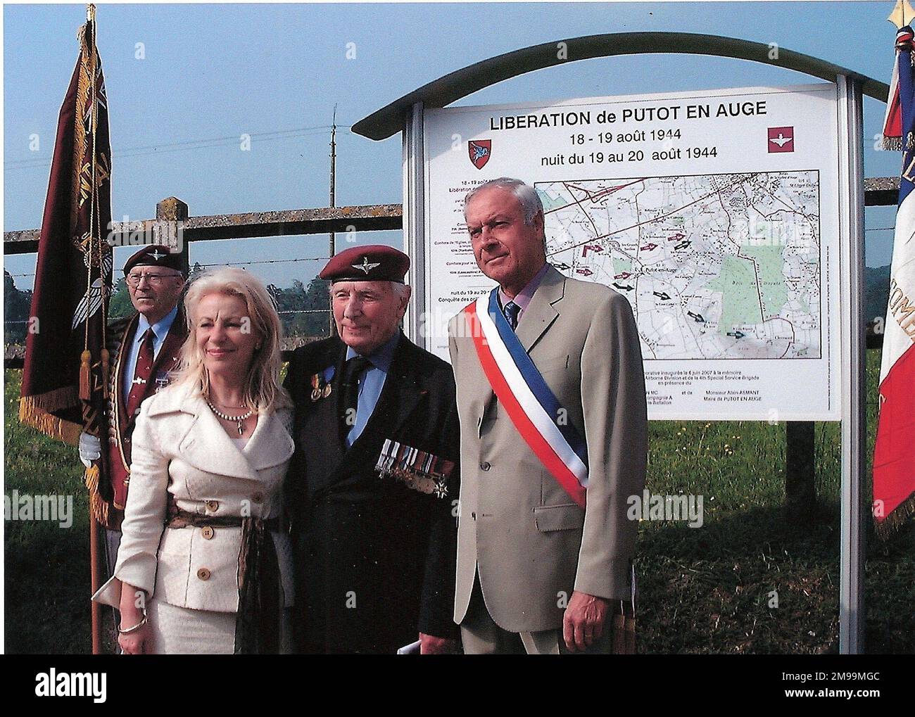 The Memorial Board, which is outside the Mairie,  was unveiled on 6 June 2007 by Major Jack Watson MC, of 13th (Lancs) Para Bn and there is a Memorial Plaque inside to him.Jack died on 14 April 2011 age 94. The Board acknowledges and details the Liberation of  Putot on 18/19 August and in particular the fighting amongst the houses and for the railway station. The picture shows the Mayor and Nicole Asmant who was greatly involved in establishing the Memorial. Stock Photo
