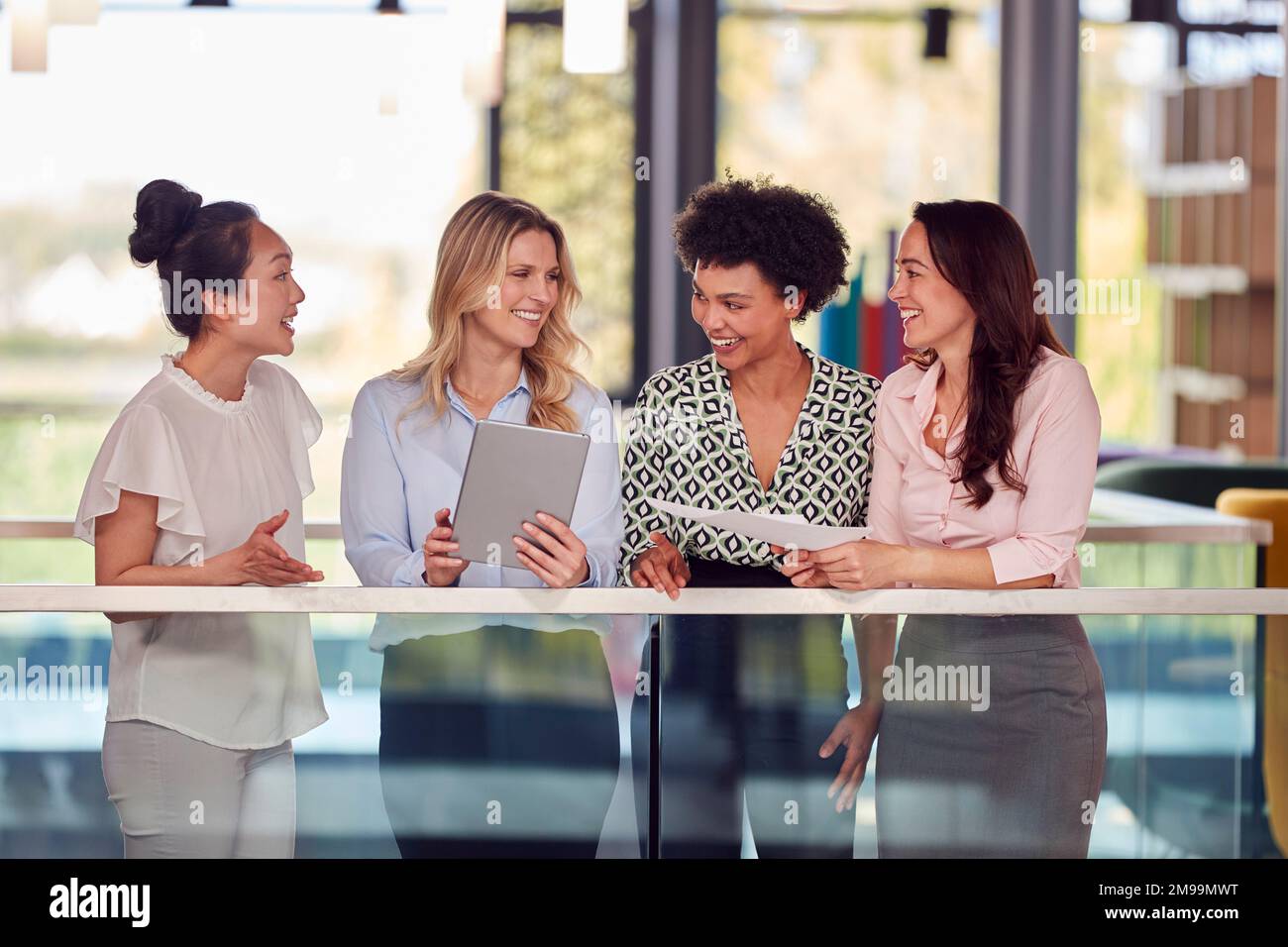 Multi-Cultural Female Business Team With Digital Tablet Meeting Inside Modern Office Building Stock Photo