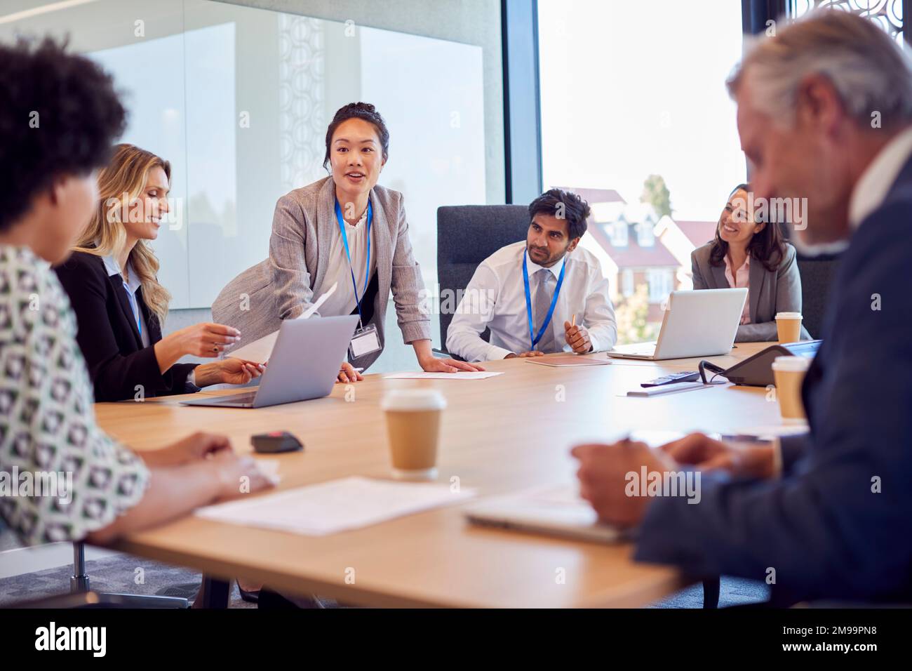 Businesswoman Leading Multi-Cultural Business Team Meeting And Collaborating Around Table In Office Stock Photo