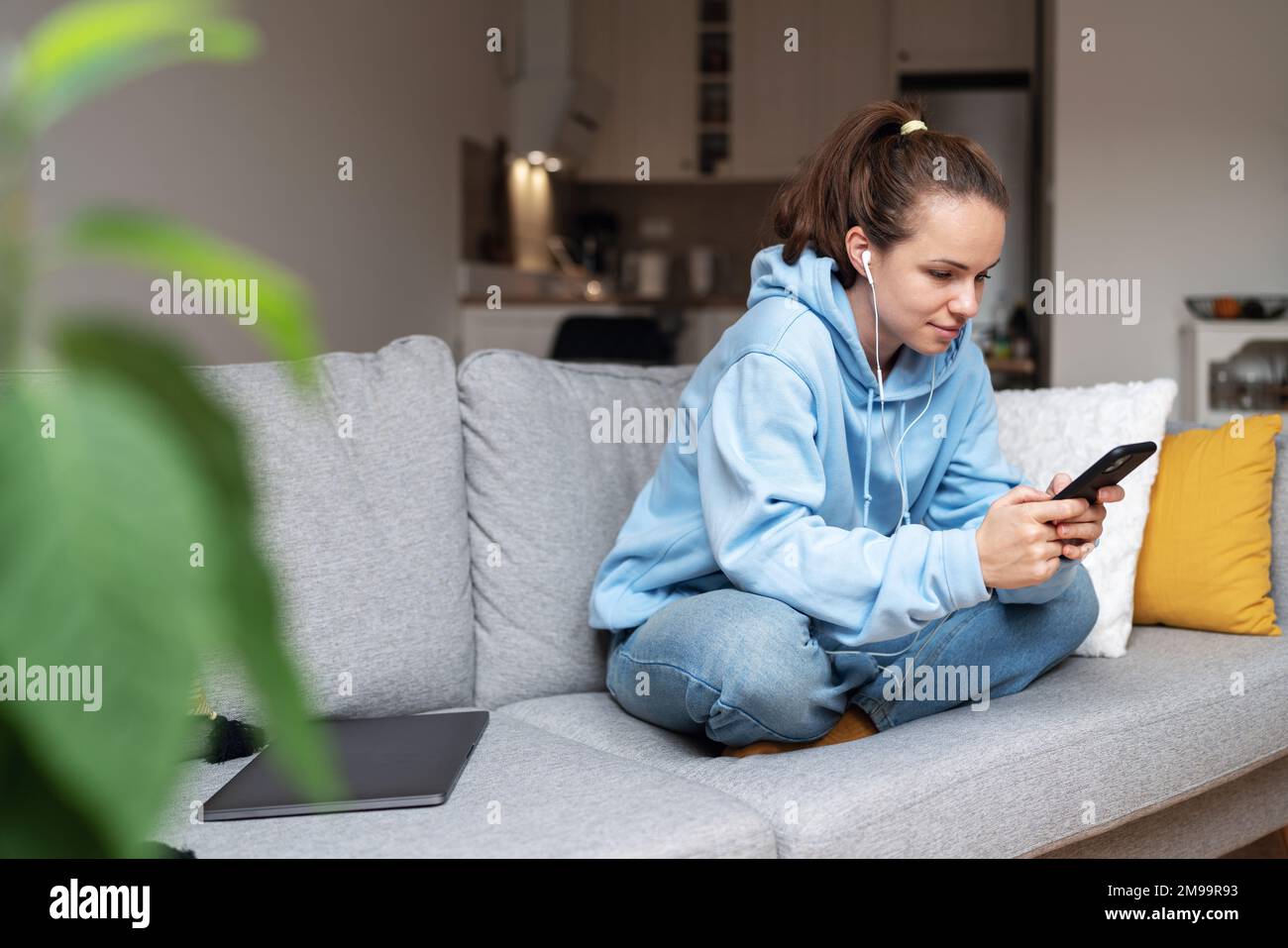 Young woman messaging online using her cell phone while sitting in ...