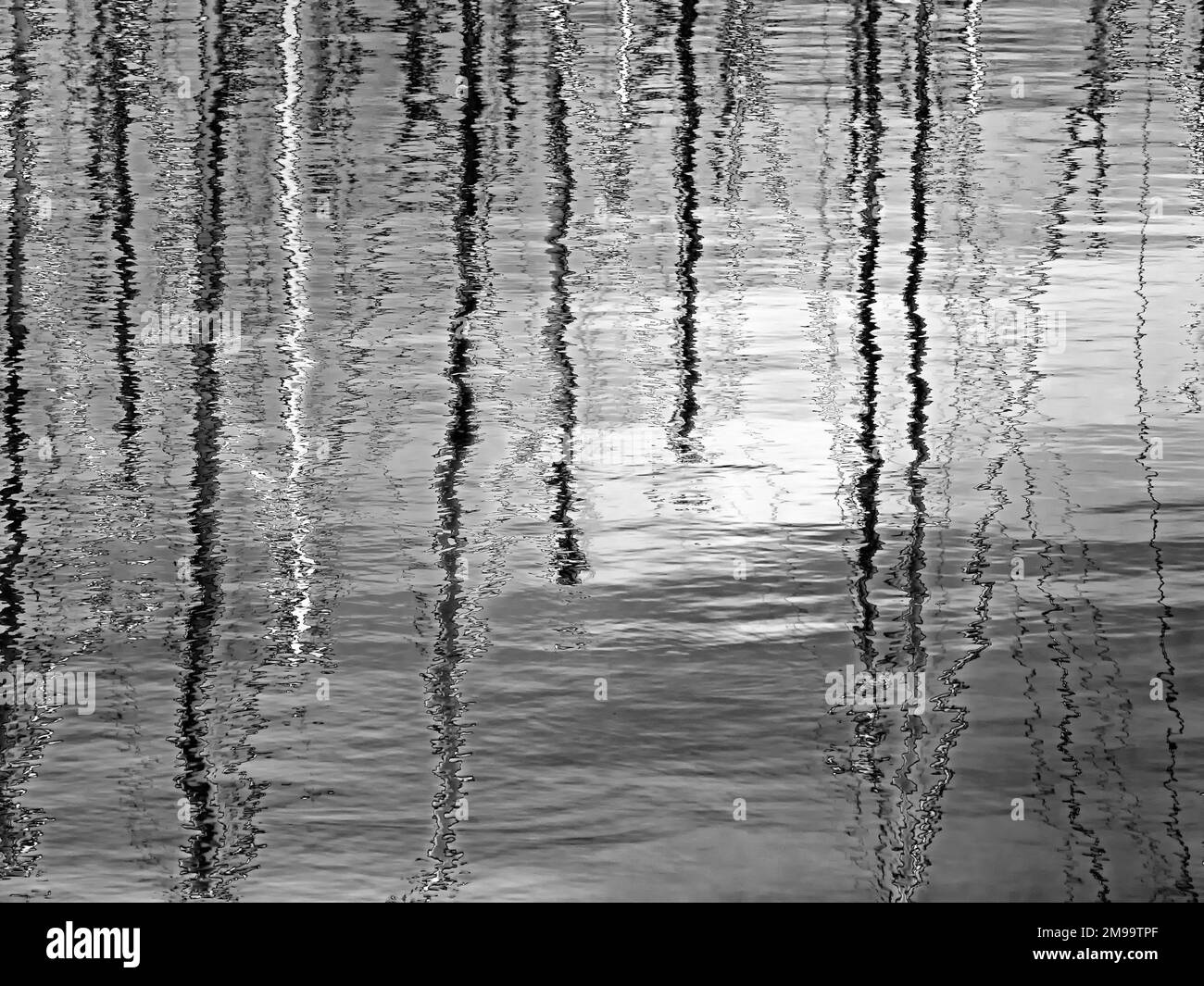 Black and white shot of abstract reflection of masts of sailboats in the water of a harbor Stock Photo