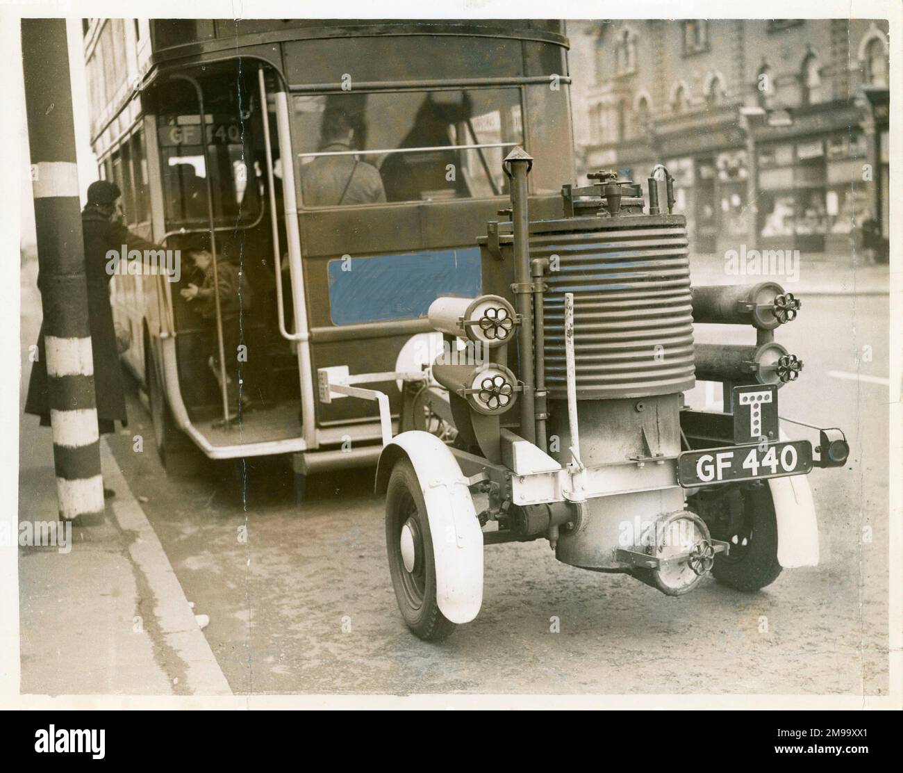 Gas Bus 'the first one [in photo] was in public service between Kingston and Epsom Downs yesterday [2 Nov 1939]. Towed by the bus, the trailer produces gas from a stove burning solid fules, which is passed to the engine through a thick hose.' Stock Photo