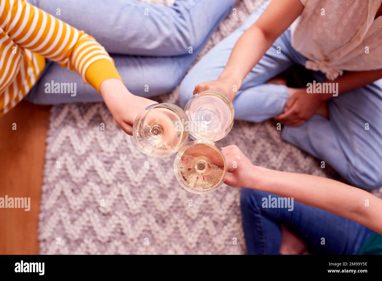 Close Up Of Female Friends Relaxing At Home Sitting In Lounge Celebrating With Glass Of Wine Stock Photo