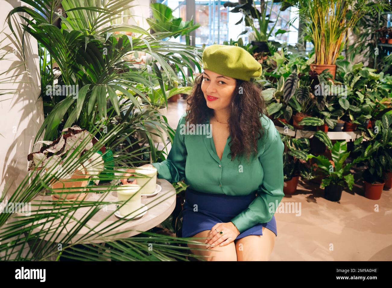 Stylish hipster woman drinking macha tea in green cafe Stock Photo