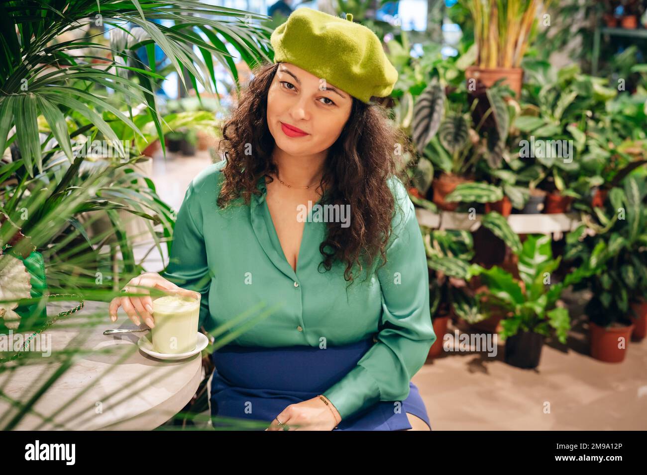 Portrait of stylish woman drinking macha tea in green cafe Stock Photo