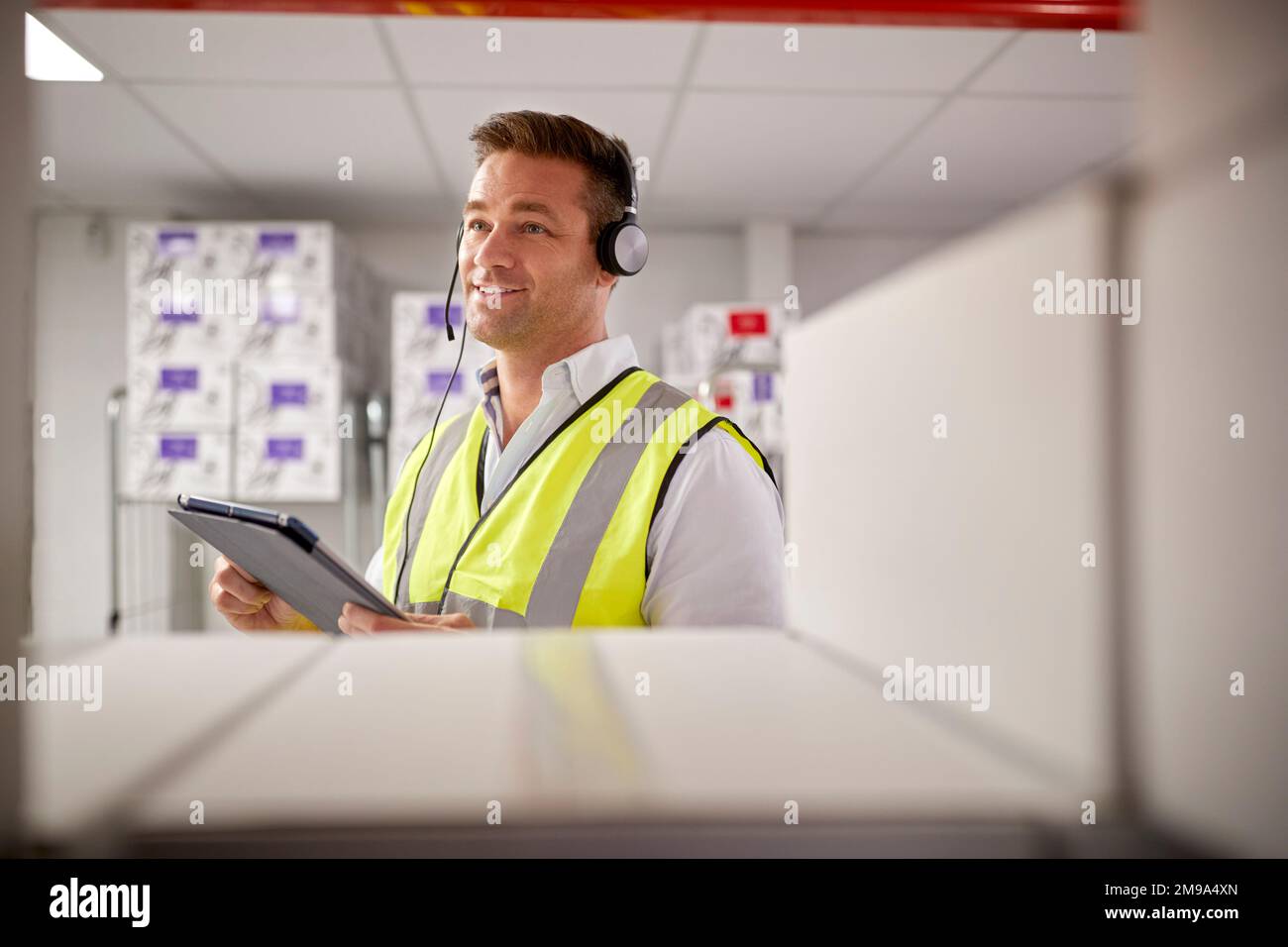 Male Worker Wearing Headset In Logistics Distribution Warehouse With Digital Tablet Stock Photo