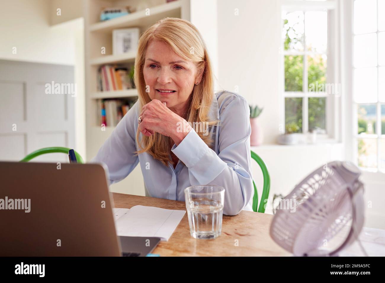 Menopausal Mature Woman Having Hot Flush At Home Cooling Herself With