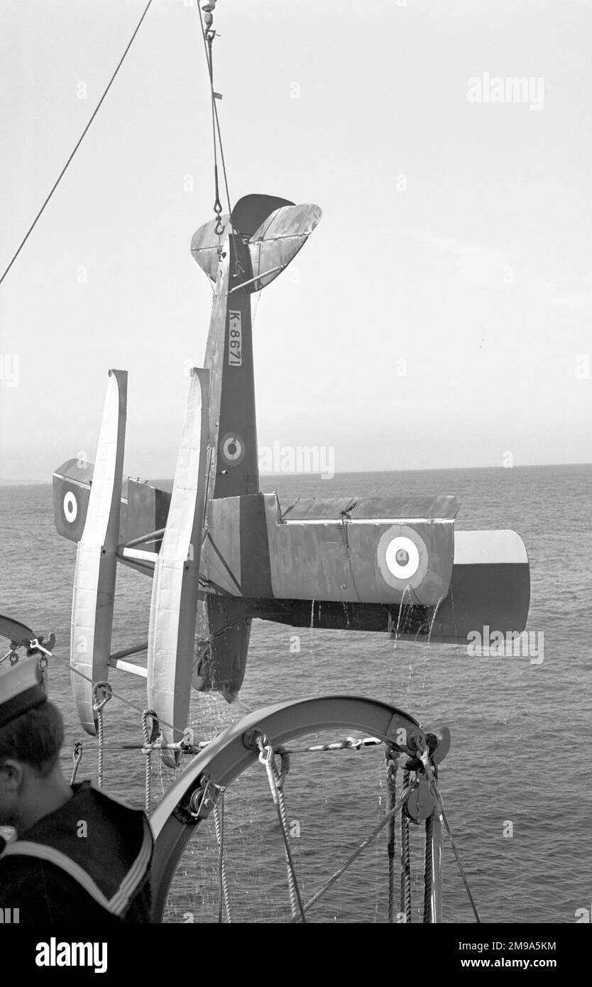 Royal Navy - de Havilland DH.82 Queen Bee K8671 (msn 5204), being recovered by cruiser HMS Newcastle after a live-fire anti-aircraft gunnery practice. The Queen Bee was a radio-controlled target drone using Tiger Moth wings, with the wooden fuselage of the DH.60 Moth to improve buoyancy in the event of an arrival and improve corrosion resistance. Stock Photo