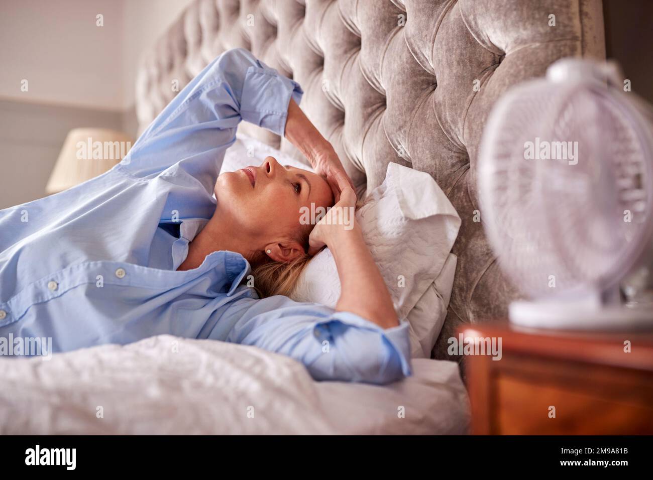 Menopausal Mature Woman Suffering With Insomnia In Bed At Home Using