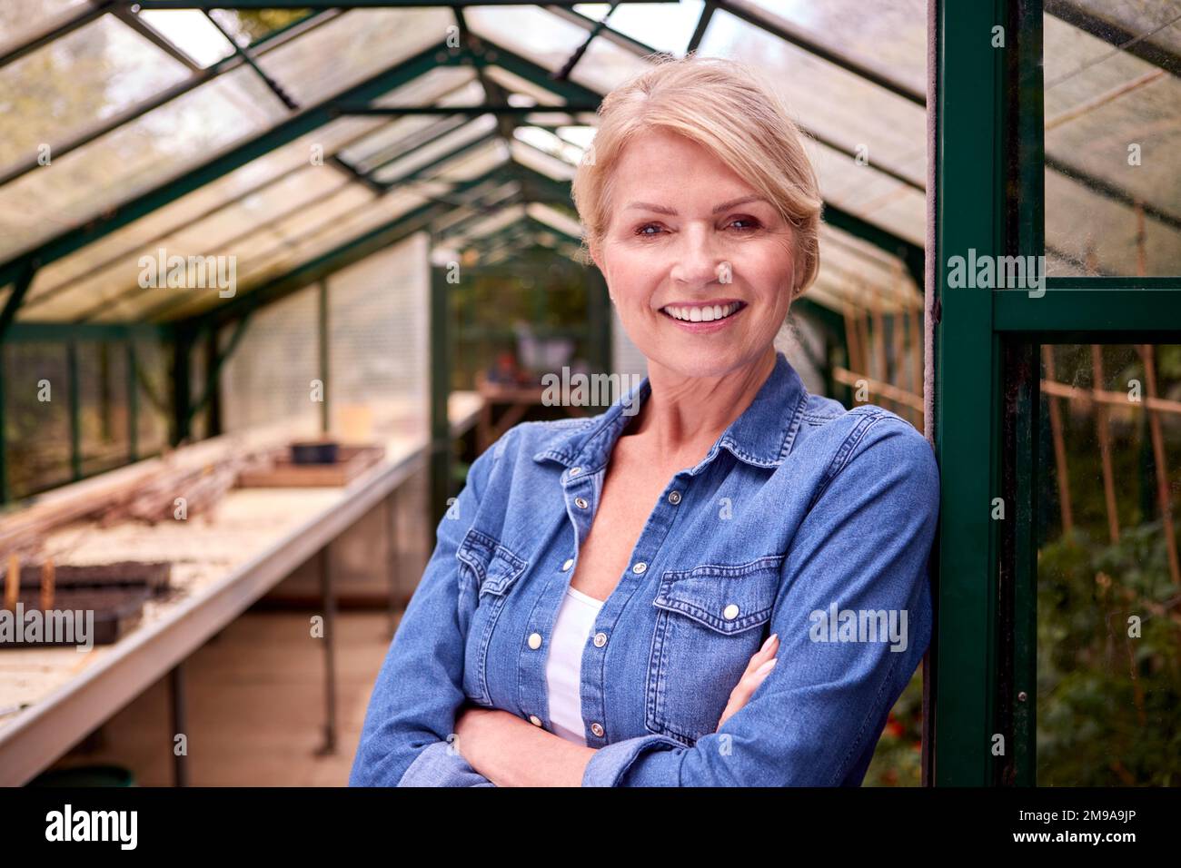 Portrait Of Mature Woman Gardening In Greenhouse At Home Stock Photo
