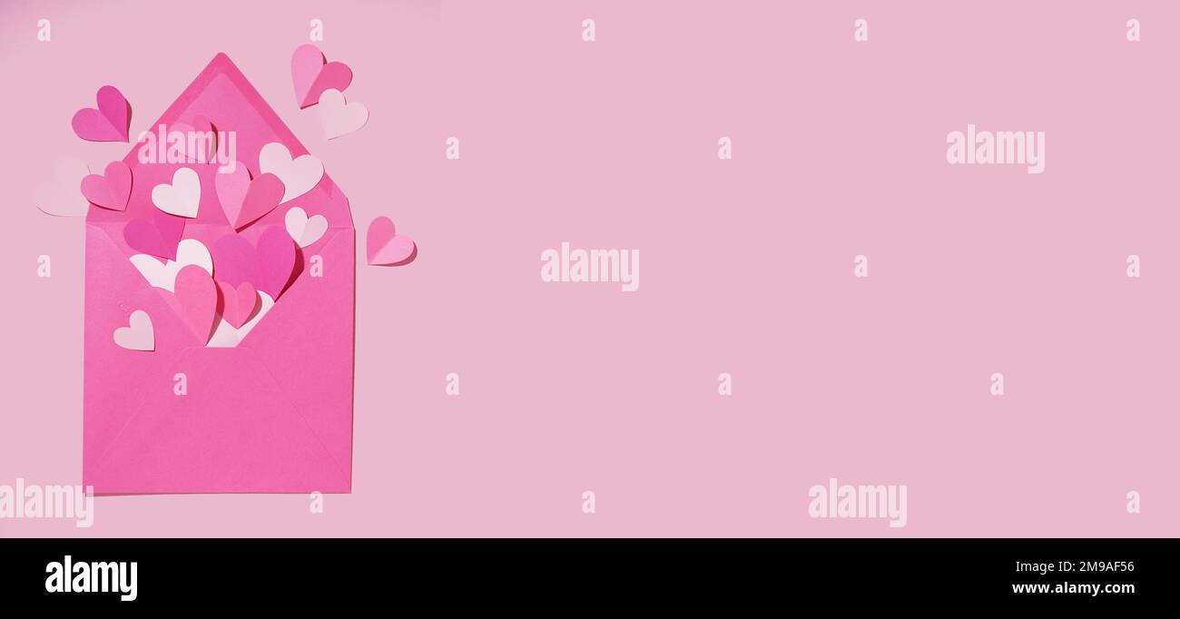 Envelope with paper hearts on pink background with space for text ...