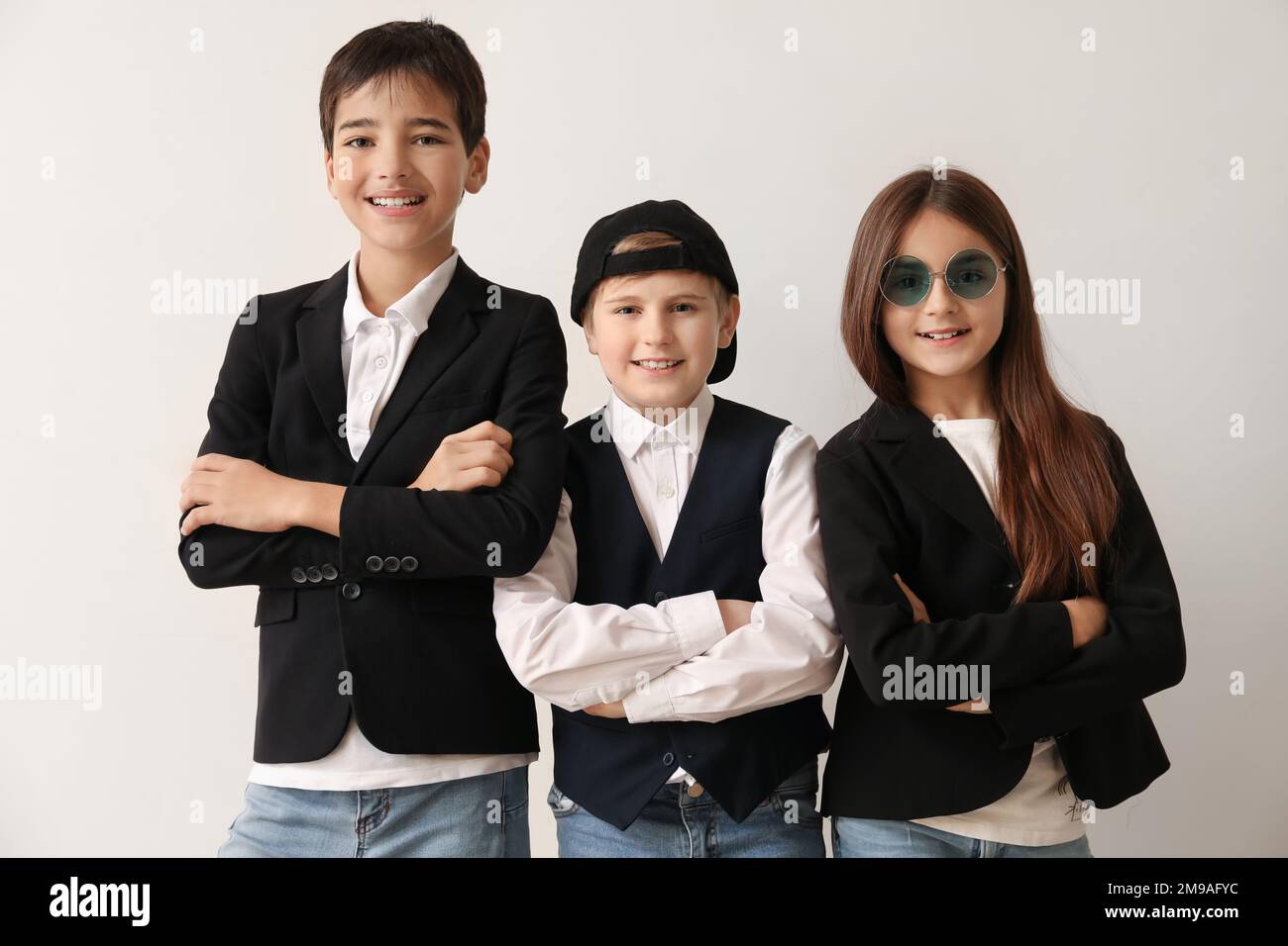Little friends in stylish school uniform near light wall Stock Photo ...