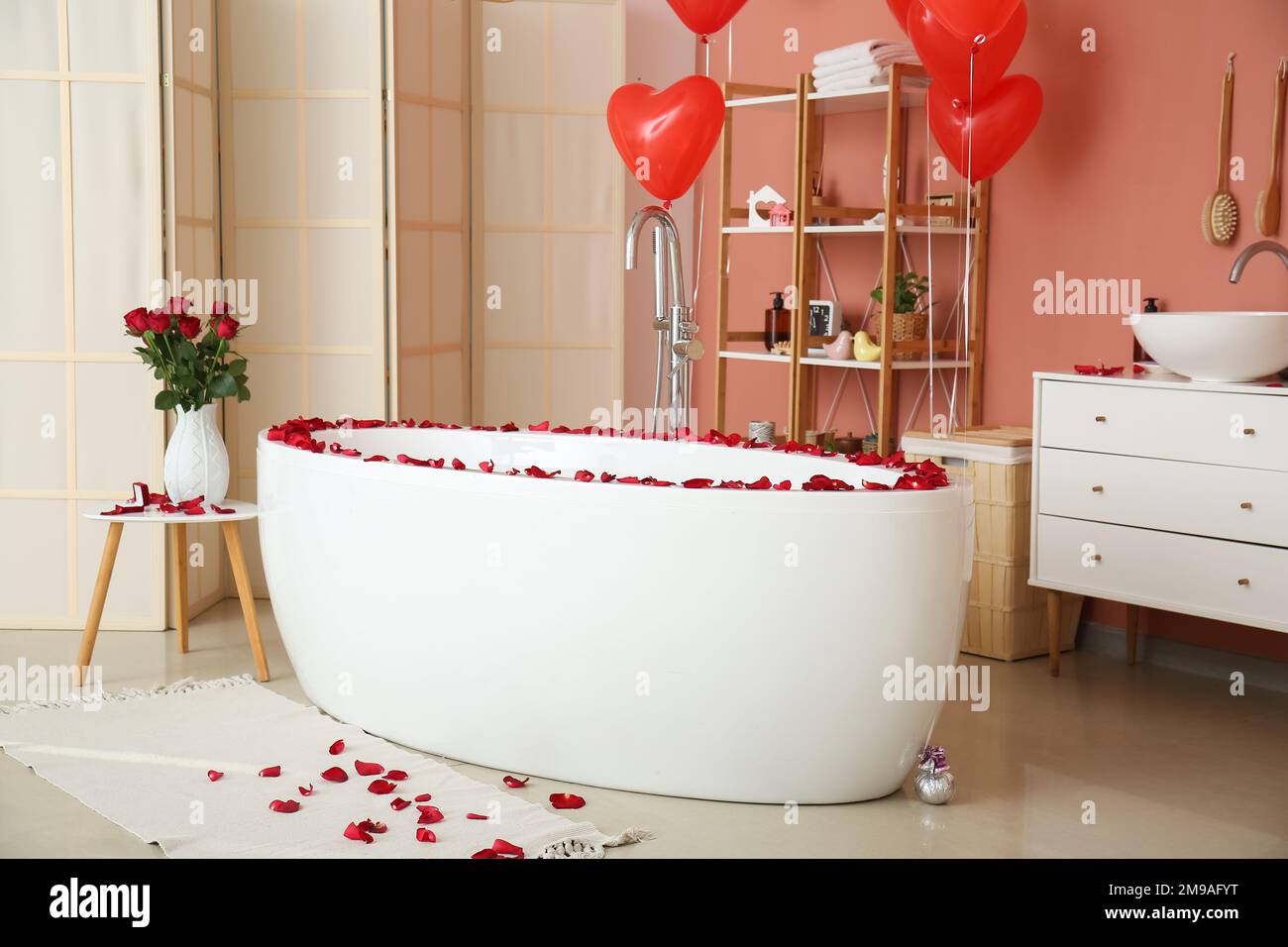 Interior of bathroom decorated for Valentine's Day with bathtub, roses