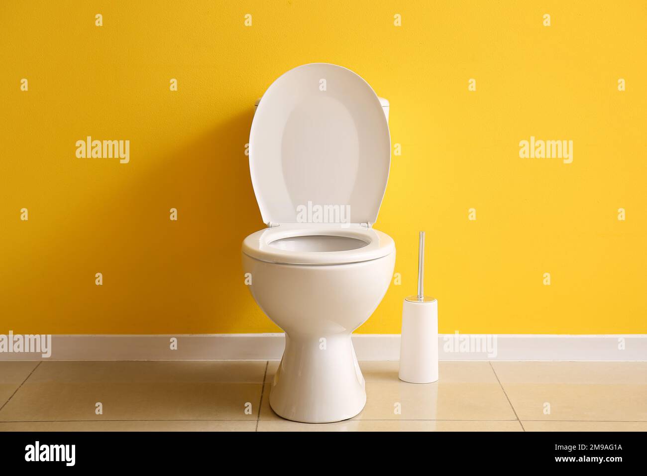 Ceramic toilet bowl and brush near yellow wall Stock Photo Alamy