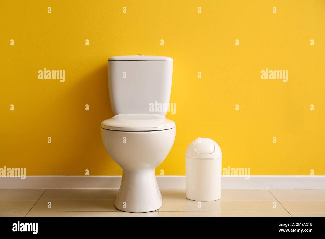 Ceramic toilet bowl and bin near yellow wall Stock Photo Alamy
