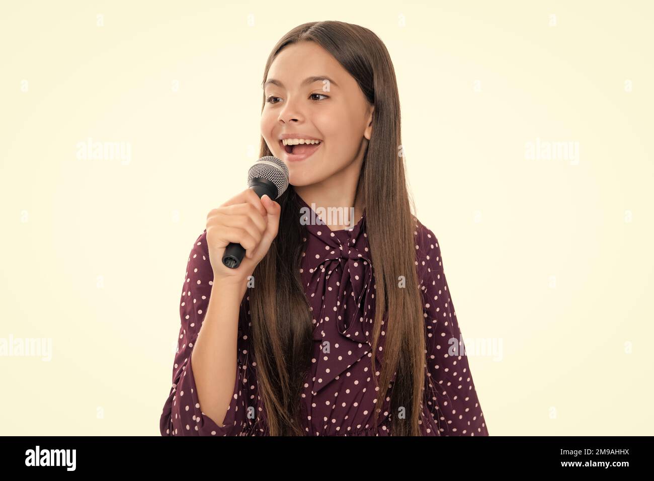 Kid singing. Emotional amazed teen girl with microphone singing against white background. Singing lovely singer girl hold microphone. Stock Photo