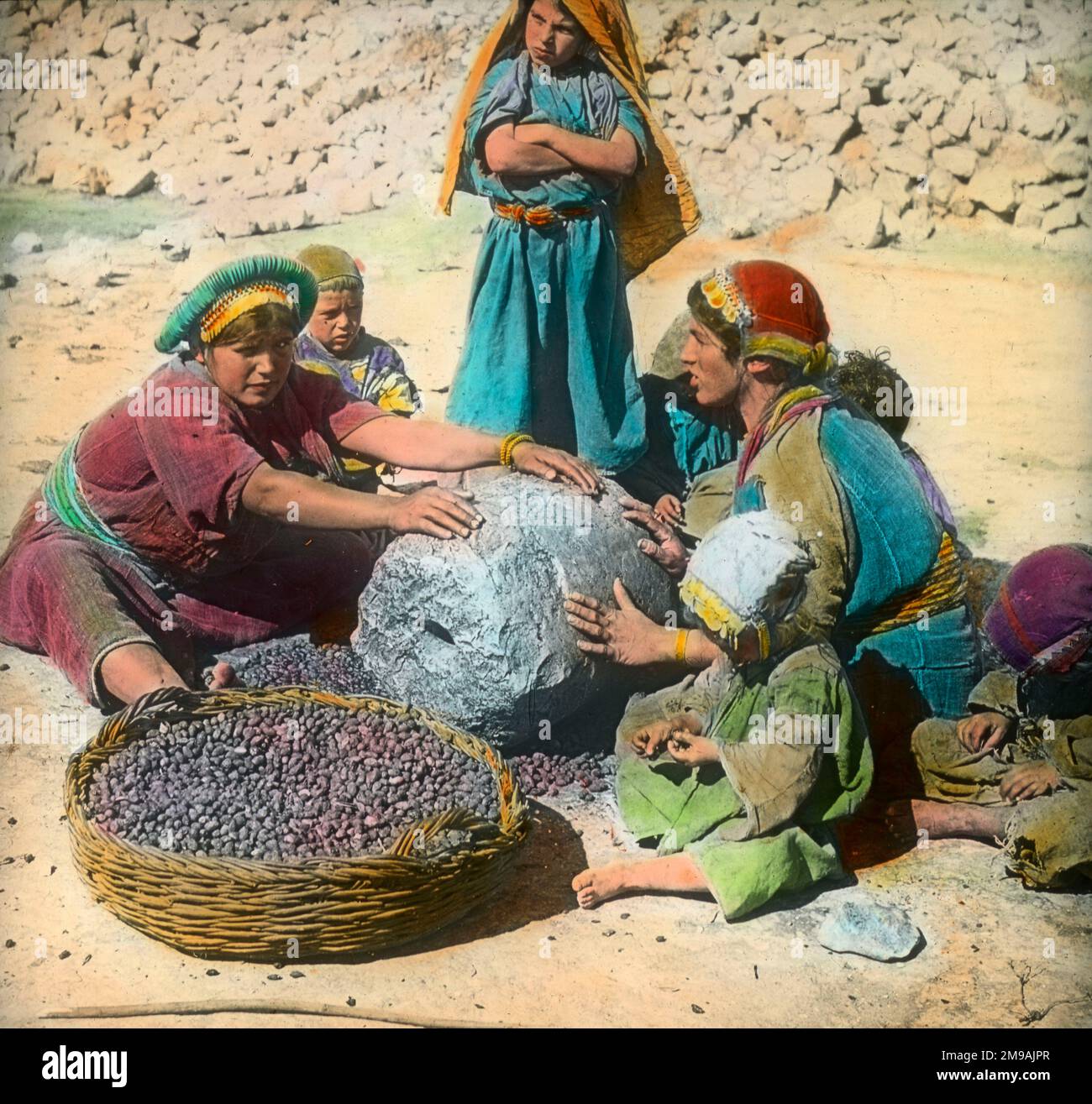 Persian women using a large grindstone, Iran Stock Photo