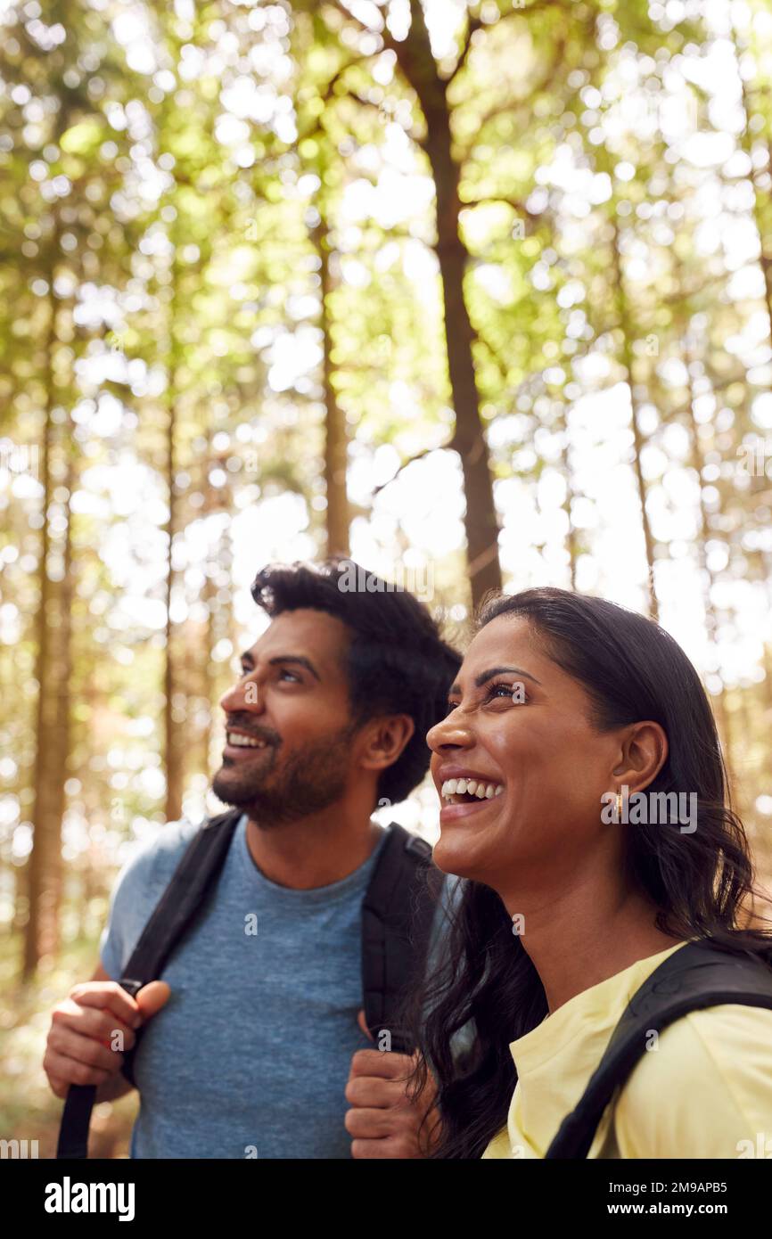 Couple With Backpacks Hiking Or Walking Through Woodland Countryside Stock Photo