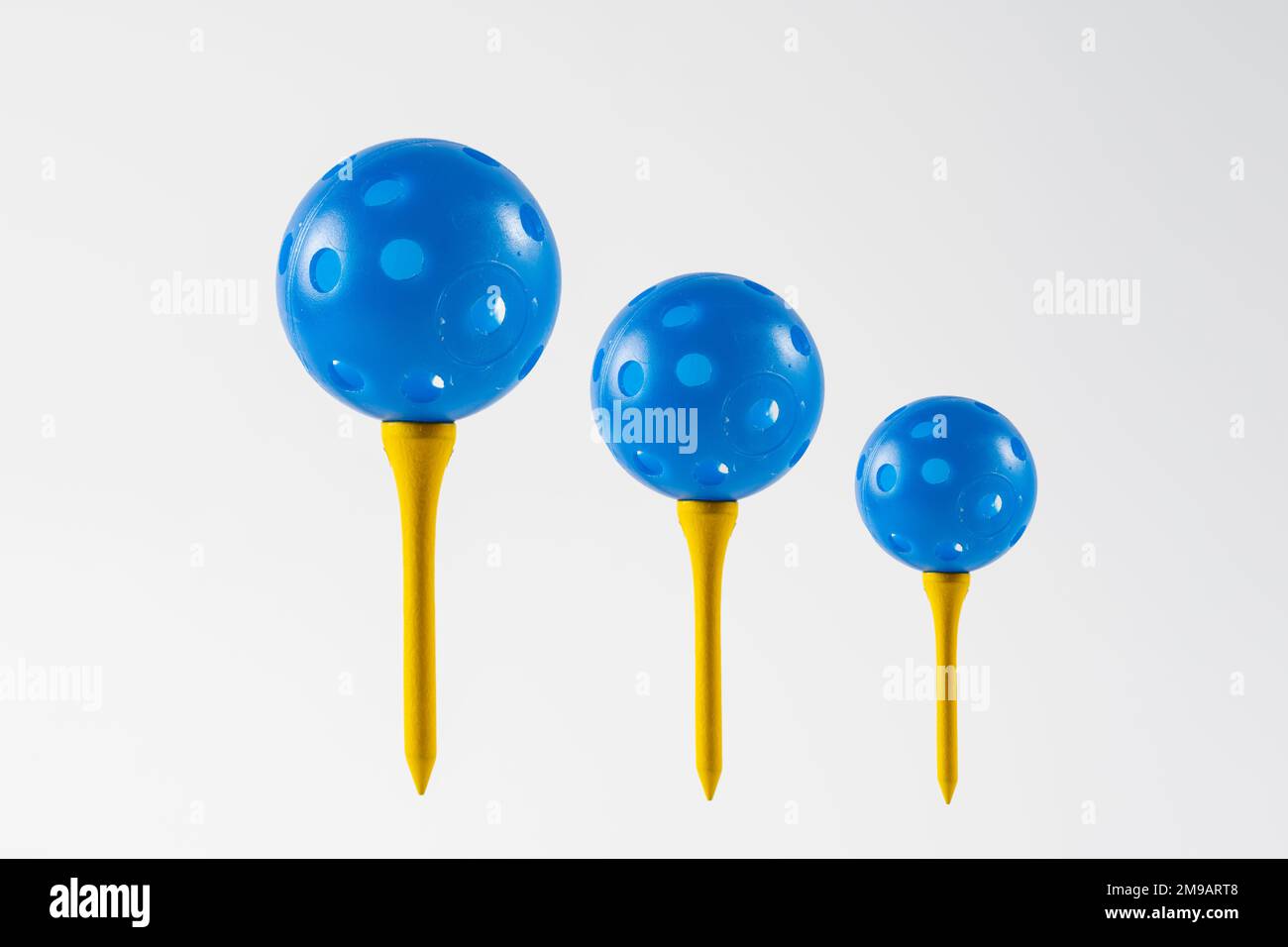 blue airflow perforated golf practice balls on a yellow tees isolated