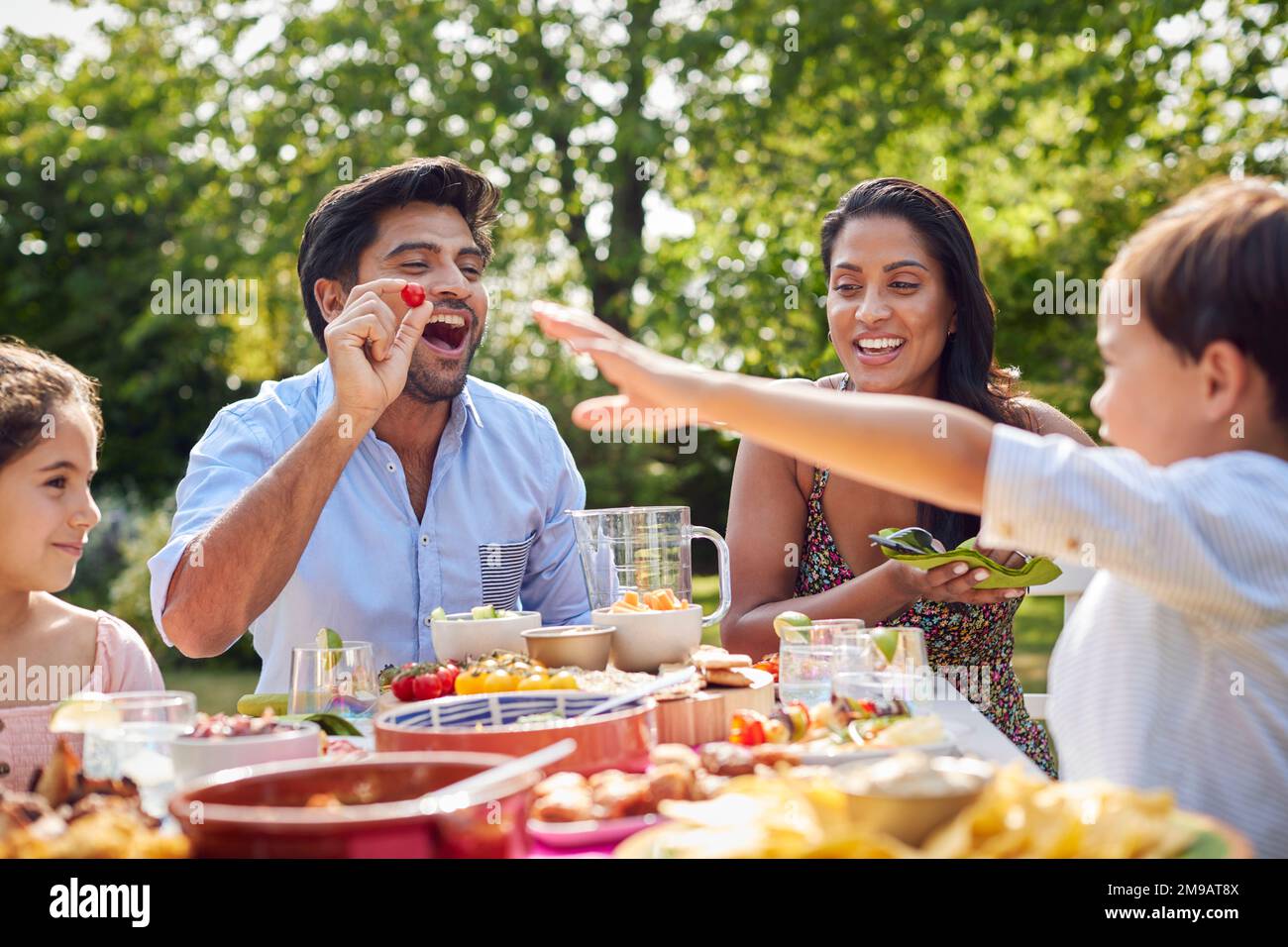 Family Eating Outdoor Meal In Garden At Home Together Stock Photo