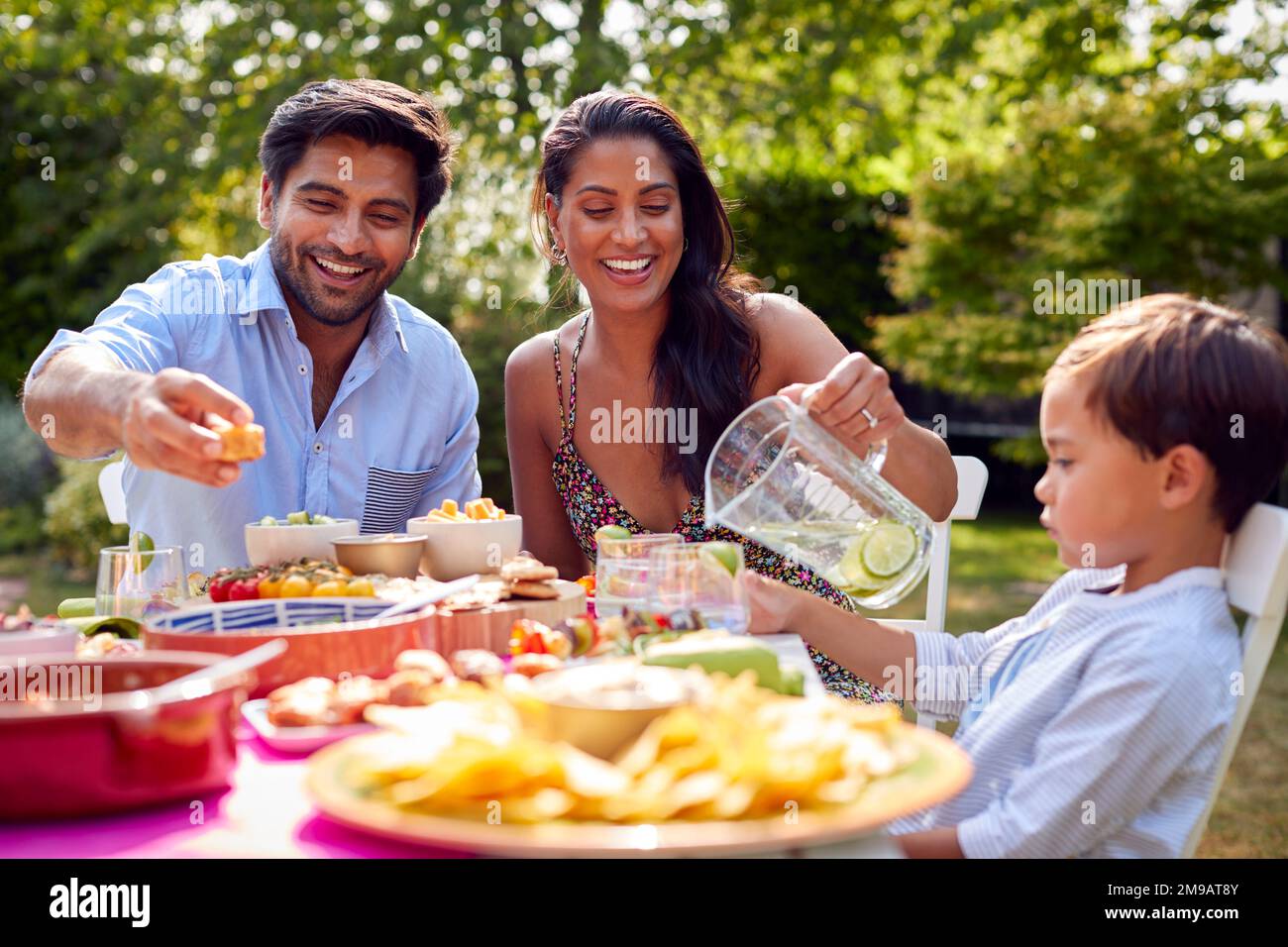 Family Eating Outdoor Meal In Garden At Home Together Stock Photo