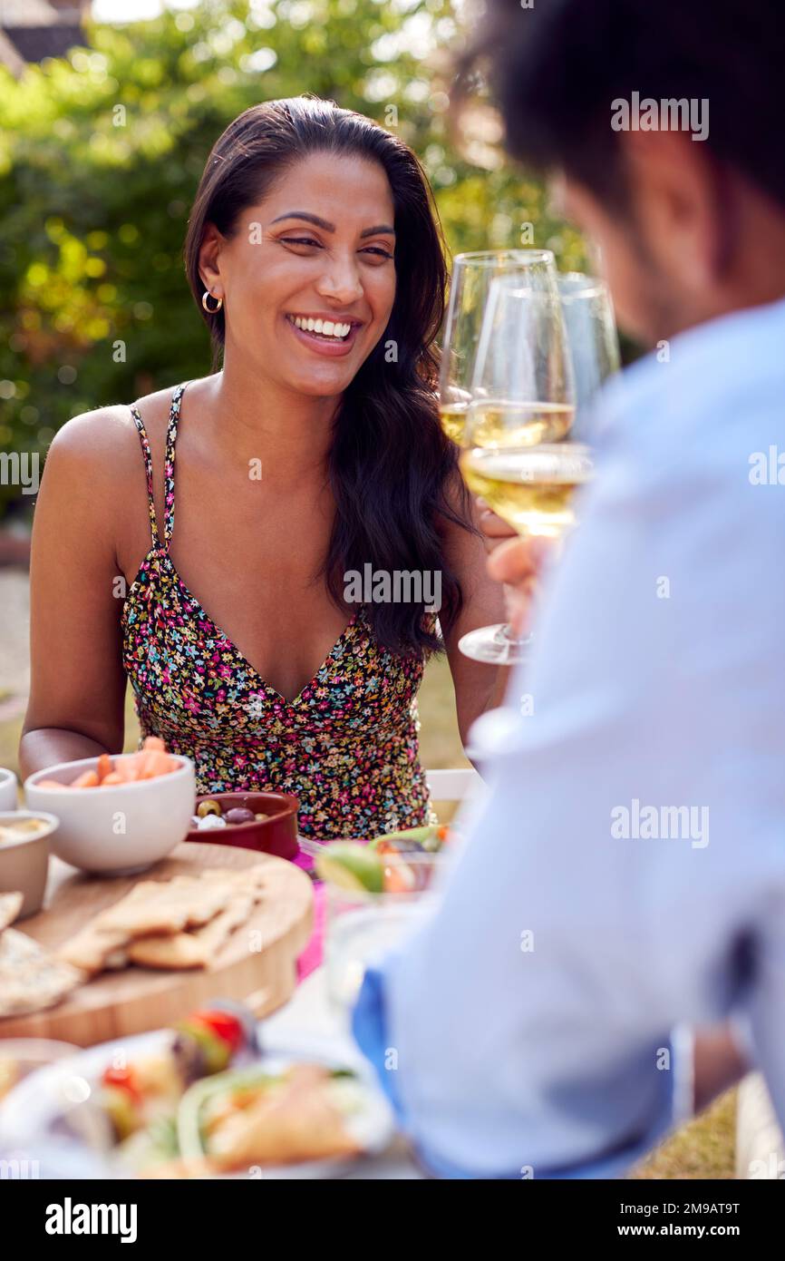 Couple Eating Outdoor Meal And Celebrating With Wine In Garden At Home Together Stock Photo